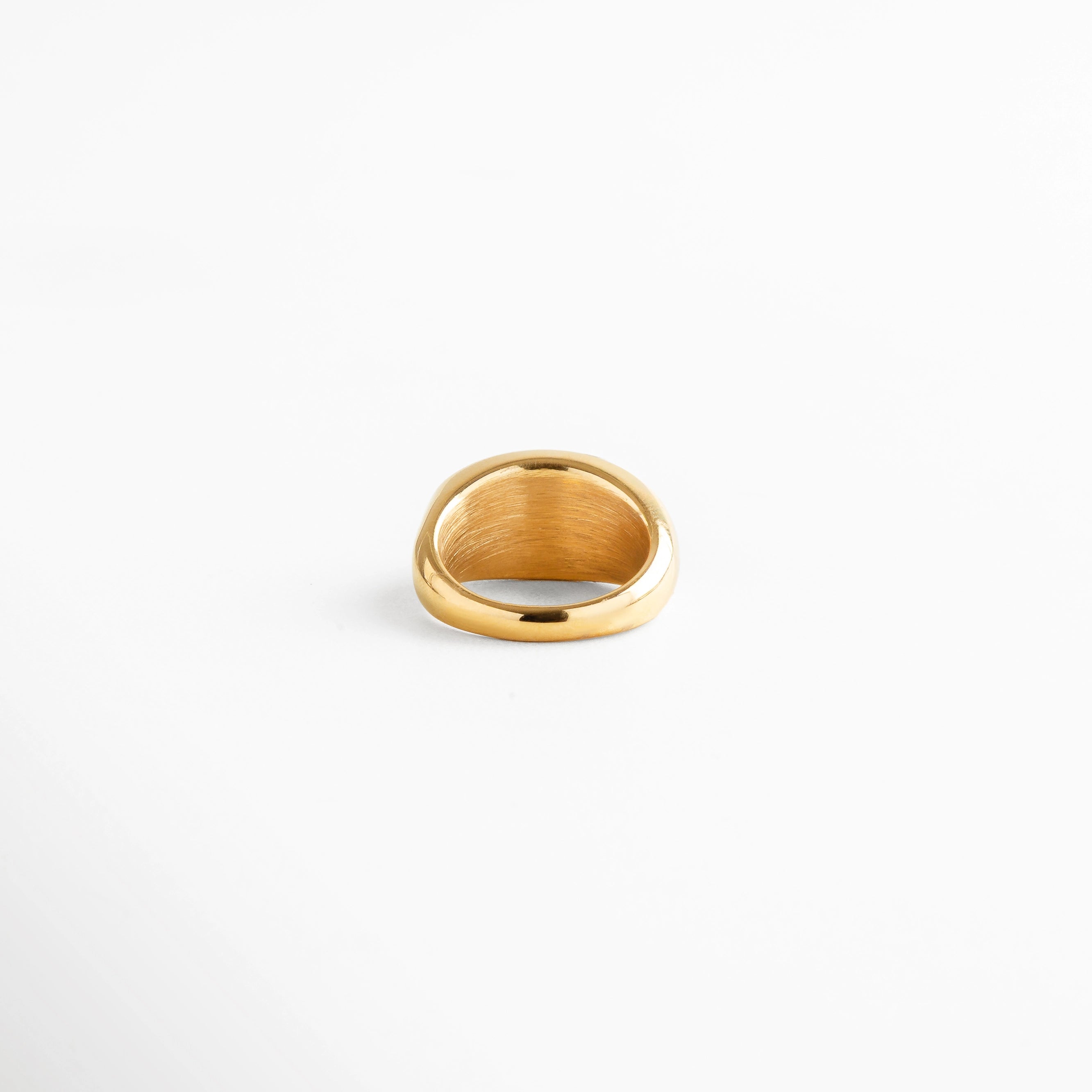 Anillo dorado de acero inoxidable con acabado pulido y piedra verde incrustada, diseño minimalista con aire sofisticado.
