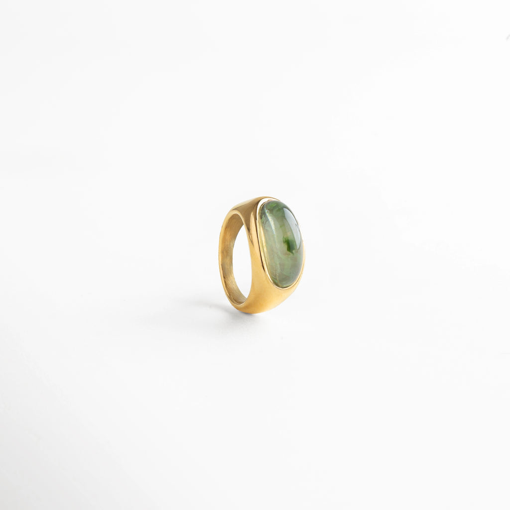 Anillo dorado con piedra verde incrustada, estilo sofisticado y moderno que aporta frescura y carácter.