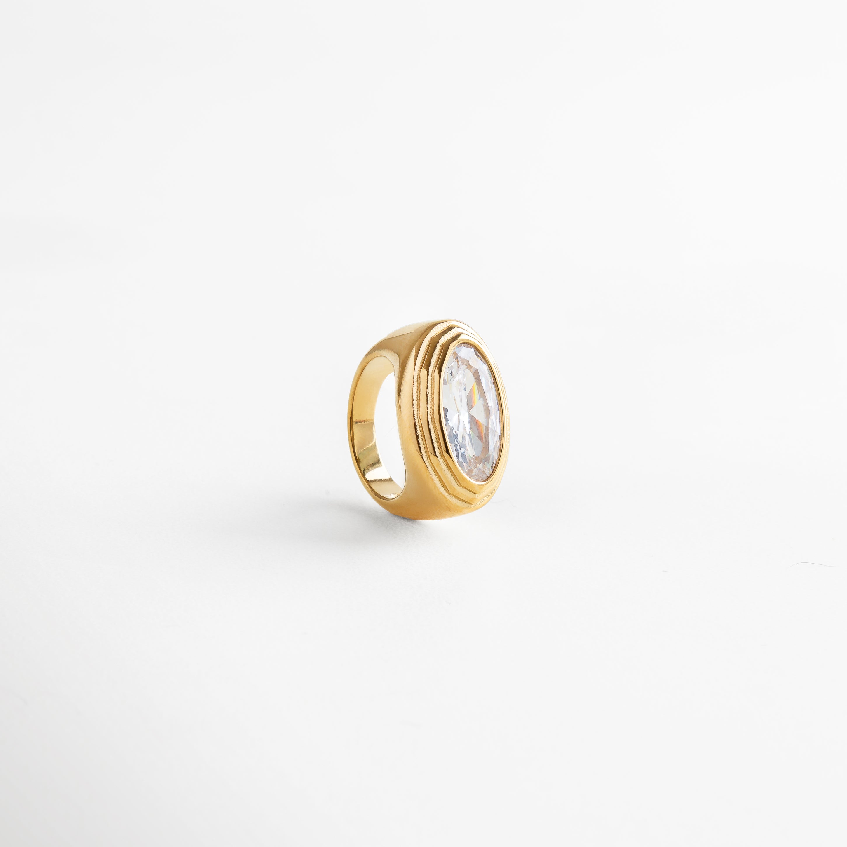 Vista superior de anillo dorado con zirconia ovalada facetada, joyería moderna y sofisticada.