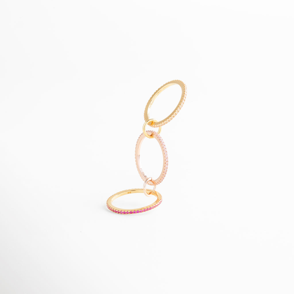 Anillo de tres aros enlazados con incrustaciones de zirconias rosas, detalle en plata ley 925 con recubrimiento en oro 18K.