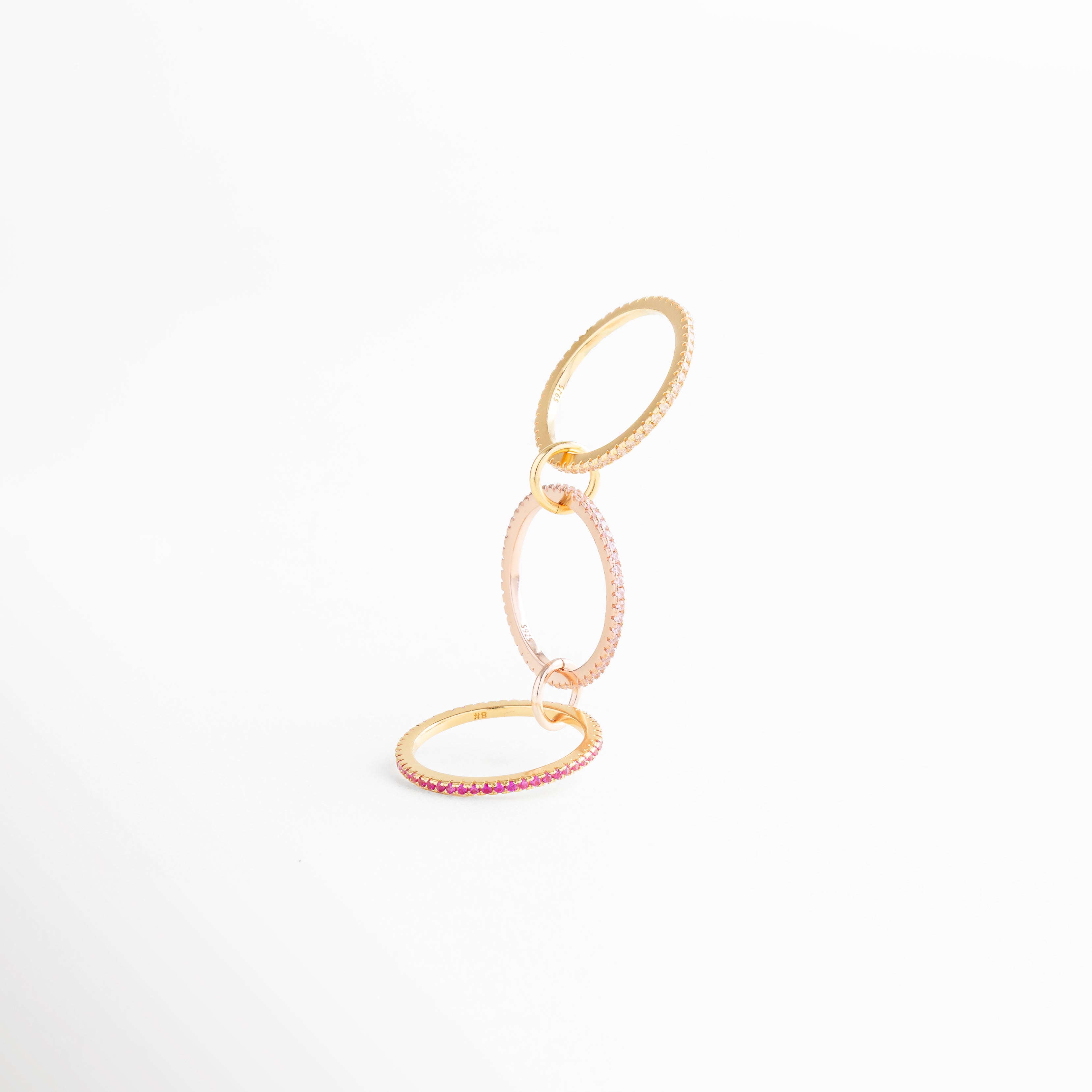 Anillo de tres aros enlazados con incrustaciones de zirconias rosas, detalle en plata ley 925 con recubrimiento en oro 18K.