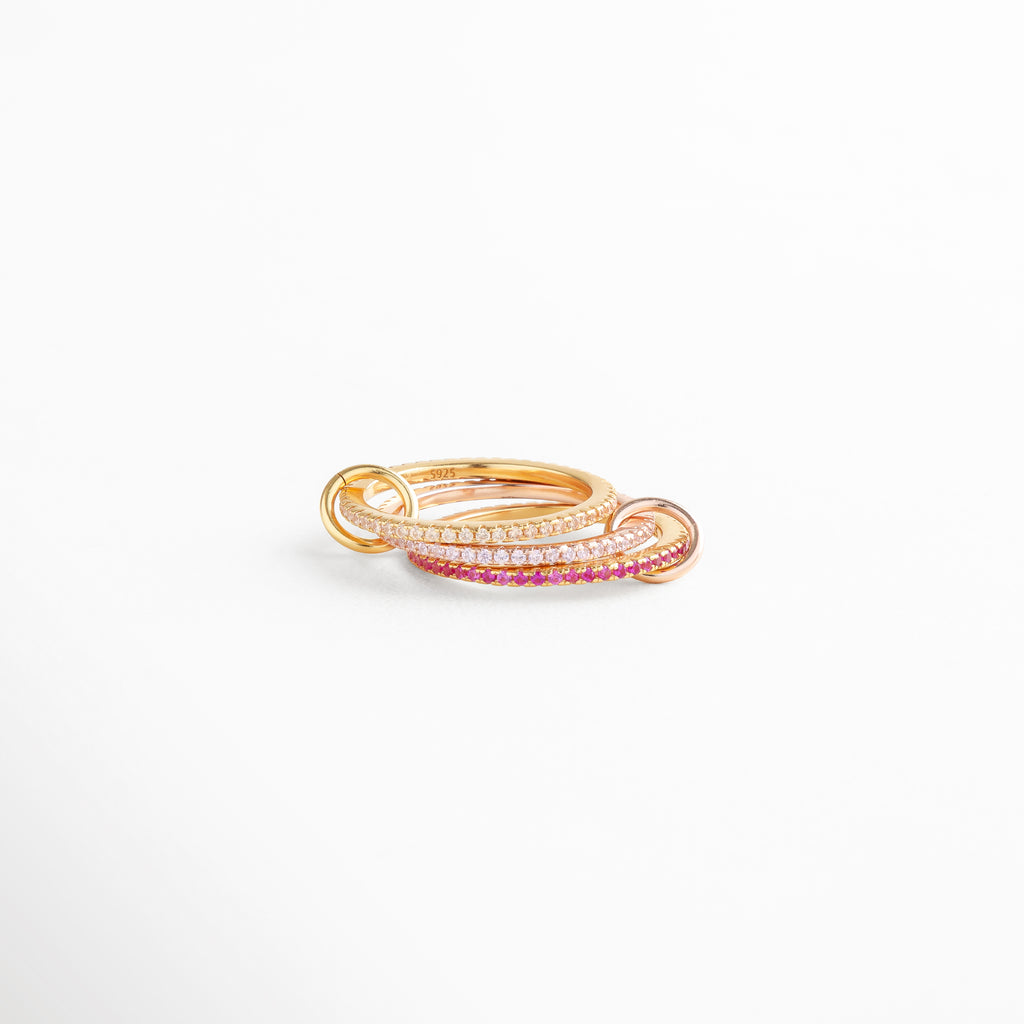 Anillo entrelazado de plata 925 con baño en oro 18K y zirconias rosas, diseño elegante y moderno de joyería fina.