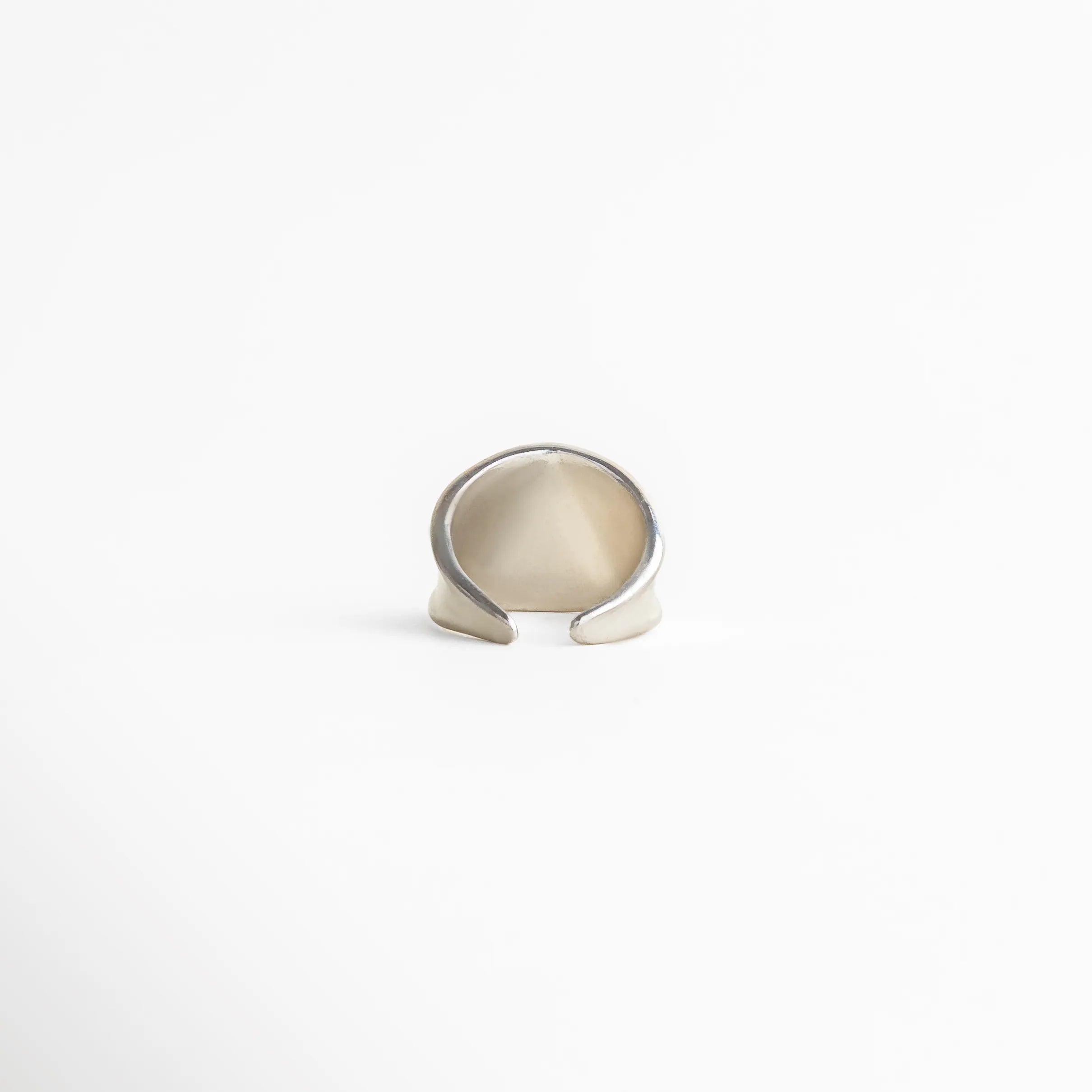 Detalle del anillo plateado de diseño abierto mostrando su estructura envolvente y acabado pulido, joyería moderna y versátil.