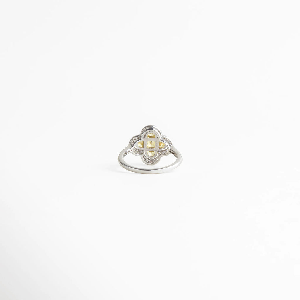 Vista superior del anillo floral para mujer con centro dorado y detalles brillantes, joyería fina de estilo clásico.