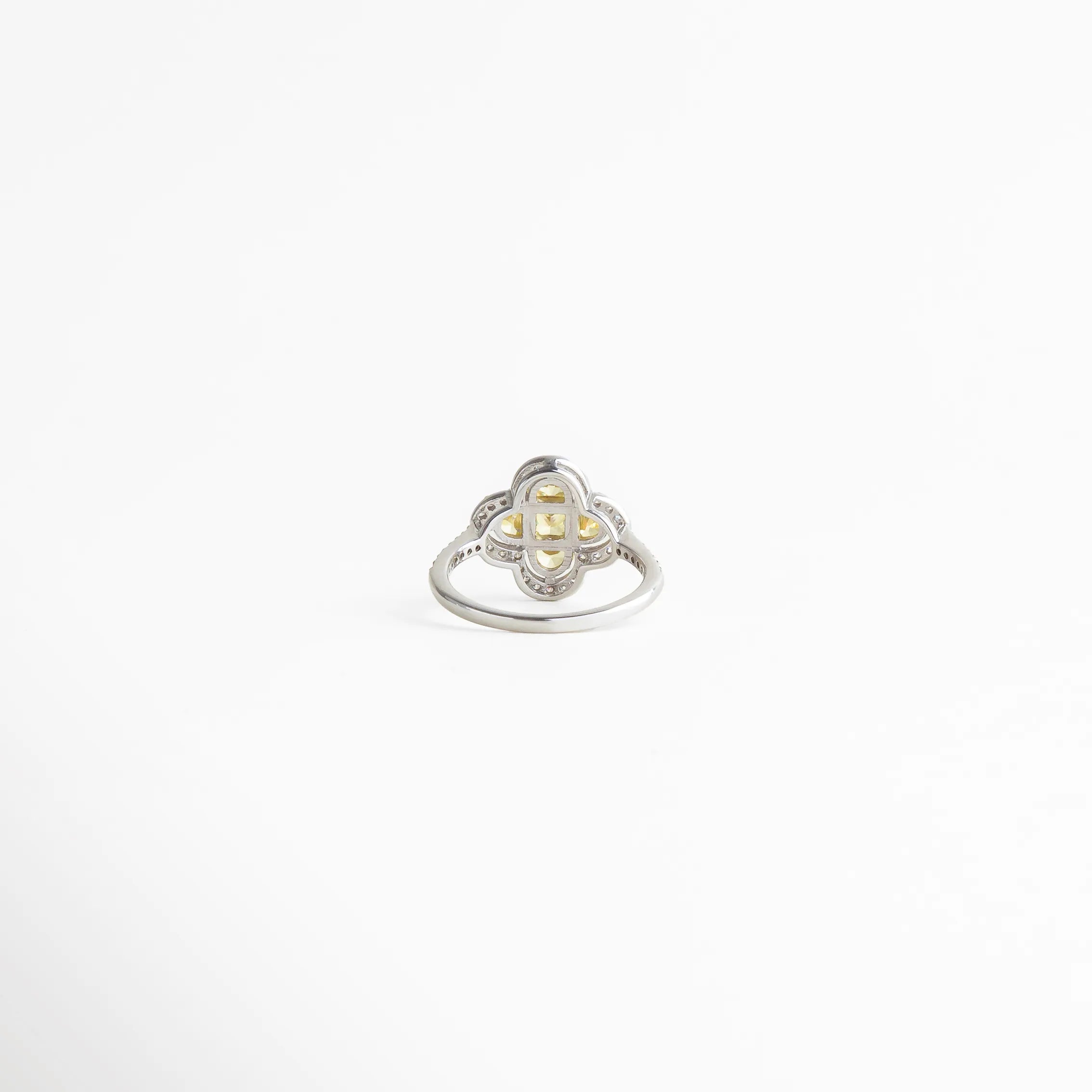 Vista superior del anillo floral para mujer con centro dorado y detalles brillantes, joyería fina de estilo clásico.