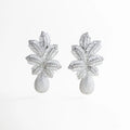 aretes plateados statement de diseño floral volumétrico, aretes largos plateados con textura brillante, joyería statement plateada estilo escultórico, aretes elegantes plateados con formas orgánicas, aretes de impacto plateados para eventos especiales, aretes llamativos plateados con volumen estructural