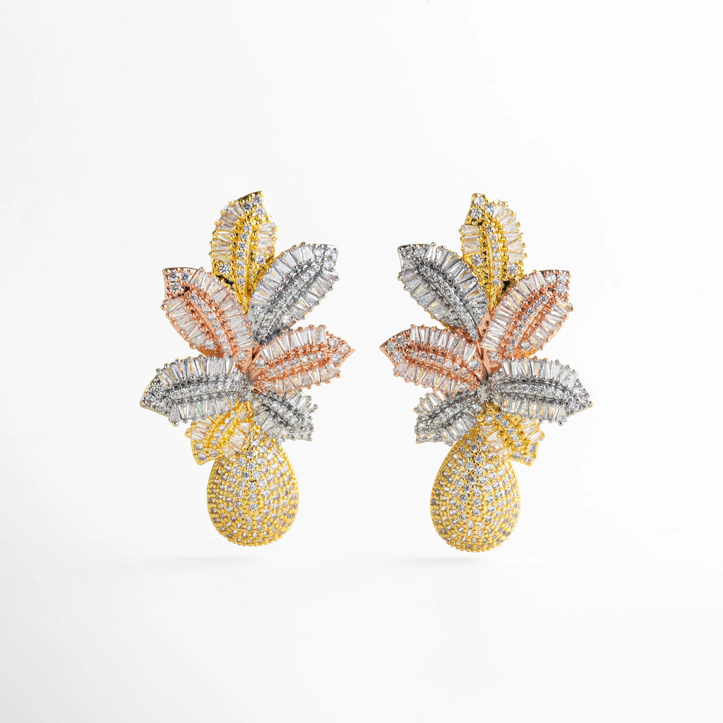 Aretes dorados con cristales multicolor corte baguette formando hojas y gota alargada cubierta de brillo estilo carnaval glam; fondo blanco minimal.