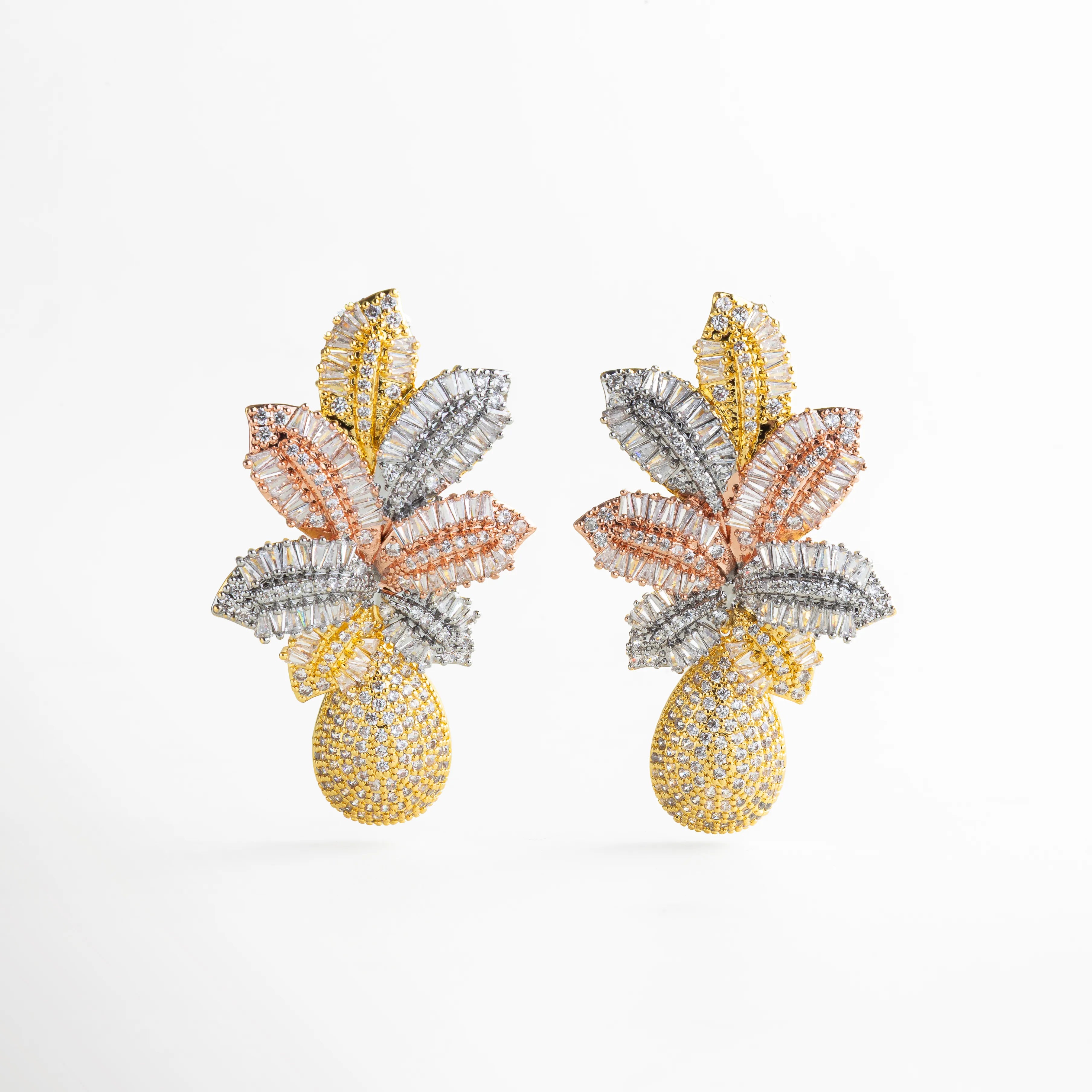 Aretes dorados con cristales multicolor corte baguette formando hojas y gota alargada cubierta de brillo estilo carnaval glam; fondo blanco minimal.