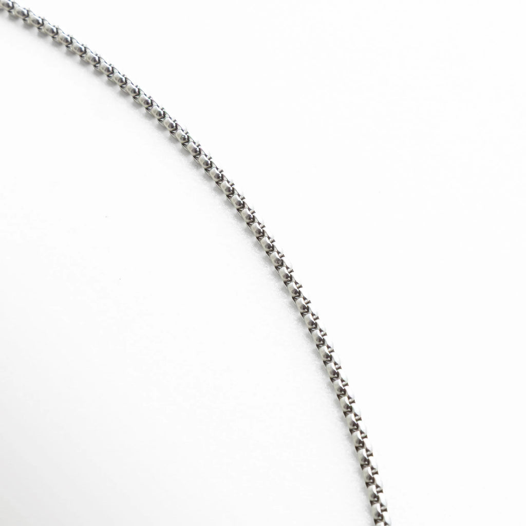 Detalle de la cadena plateada con eslabones uniformes y textura pulida. La toma resalta la fineza del trabajo metálico, que aporta brillo y ligereza visual al conjunto.