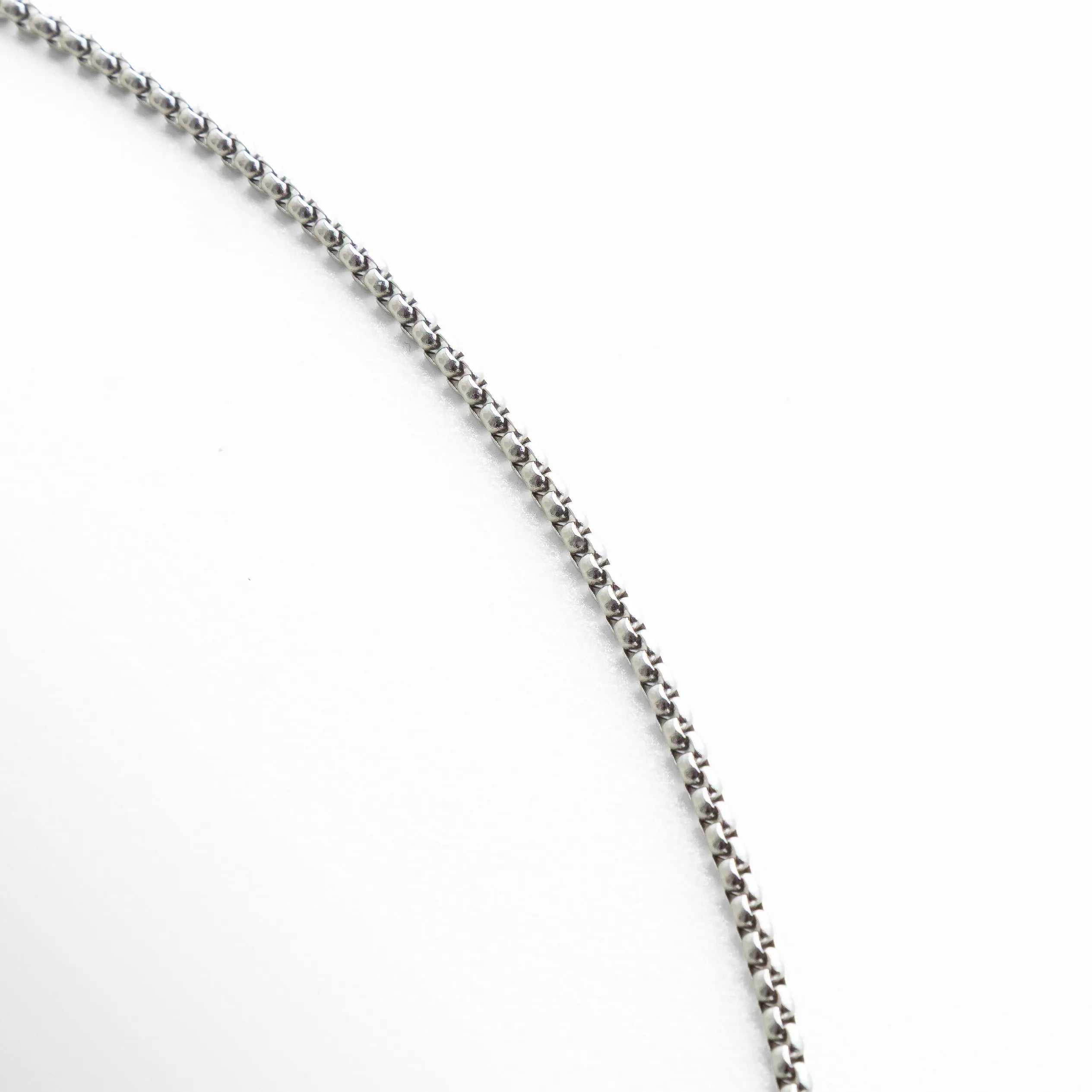 Detalle de la cadena plateada con eslabones uniformes y textura pulida. La toma resalta la fineza del trabajo metálico, que aporta brillo y ligereza visual al conjunto.