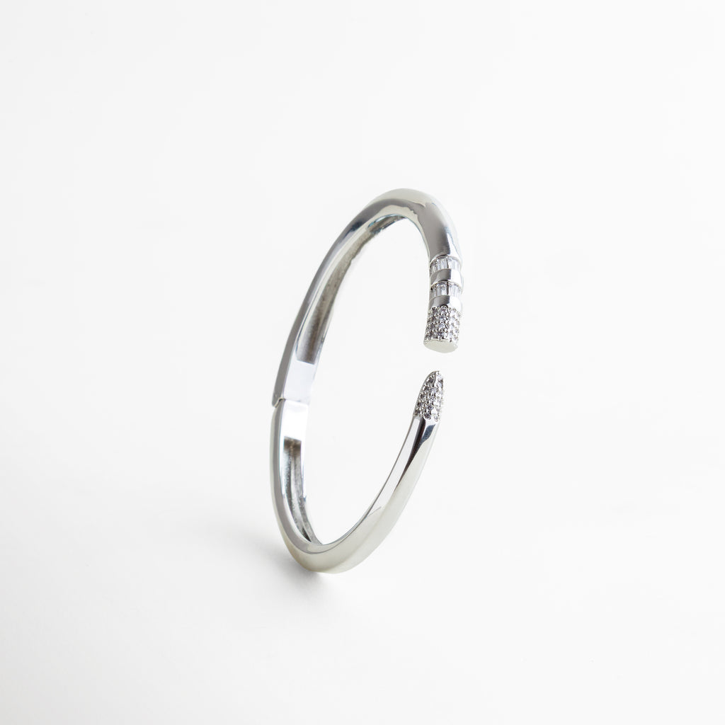 pulsera rígida plateada vista lateral diseño limpio, pulsera de acero plateado perfil delgado moderno, pulsera abierta plateada con acabado brillante, pulsera minimalista vista lateral elegante, joya plateada contemporánea detalle lateral