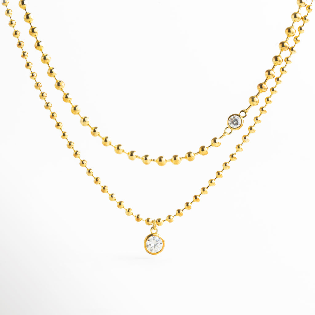 collar dorado doble cadena con zirconias, collar dorado elegante con detalle de zirconia, collar fino dorado con colgante brillante, joyería dorada collar doble minimalista, collar femenino dorado con zirconia central