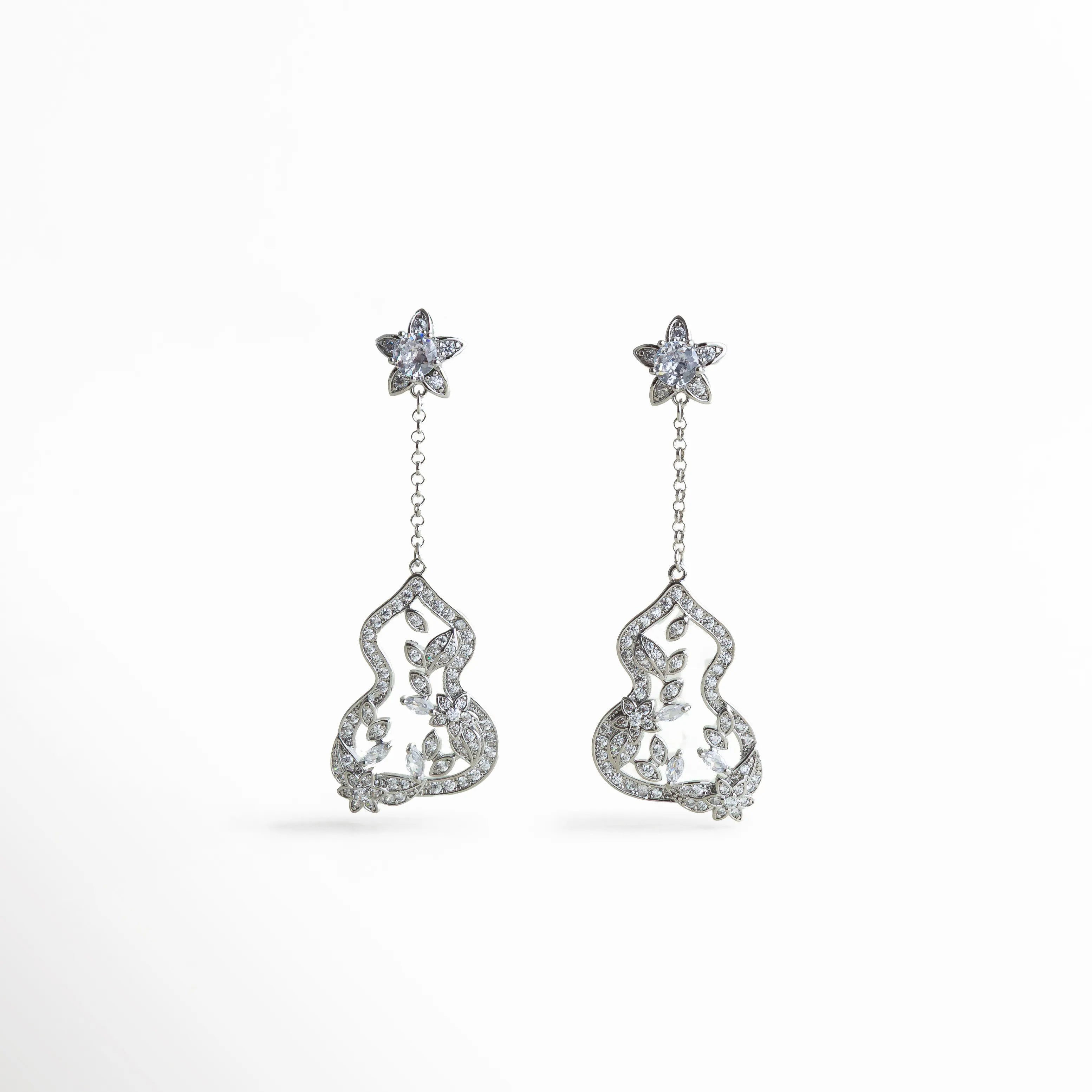 Aretes plateados con flores de zirconia y detalle colgante en forma orgánica, diseño romántico con brillo delicado ideal para ocasiones especiales.