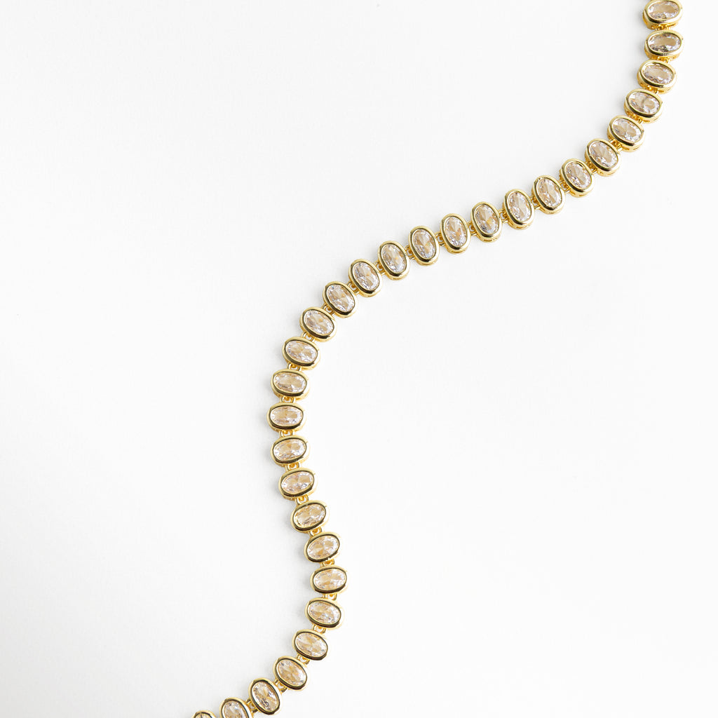 Collar dorado extendido con zirconias y diseño uniforme, Composición de collar elegante con brillo continuo, Collar dispuesto mostrando su longitud y detalles, Diseño completo de collar con zirconias brillantes, Collar de 40 cm con acabado dorado y piedras decorativas
