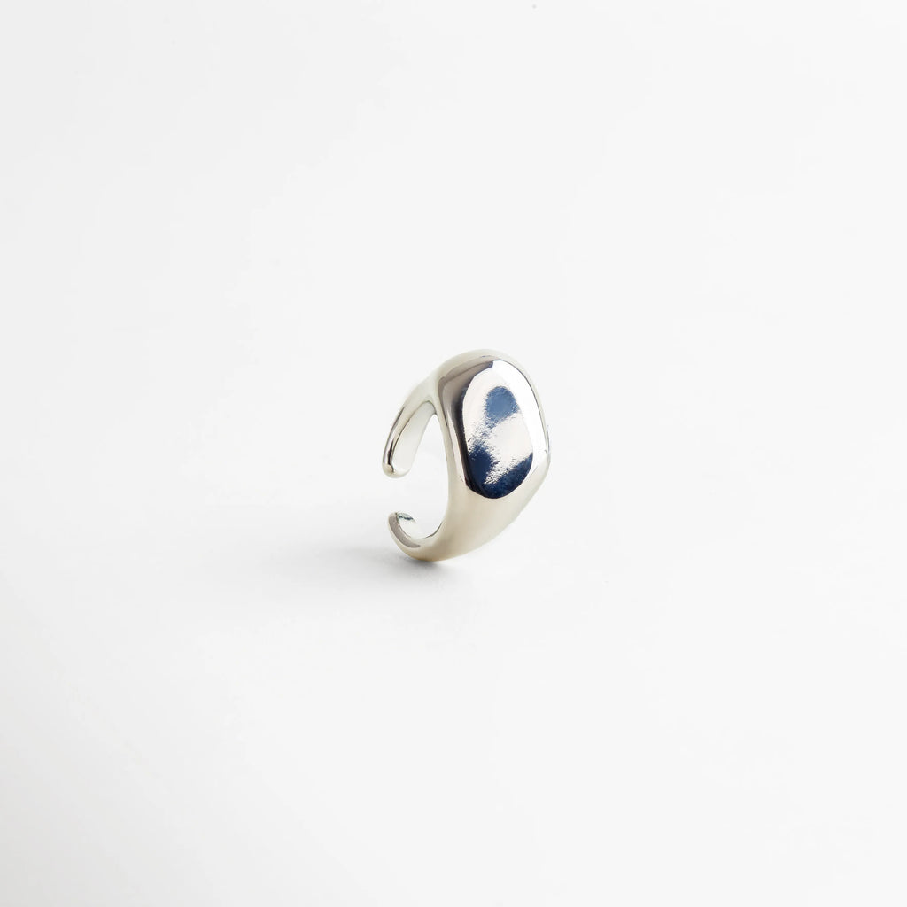 Anillo plateado ajustable con acabado pulido tipo espejo, diseño contemporáneo de superficie curva y bordes suaves que reflejan la luz con elegancia.