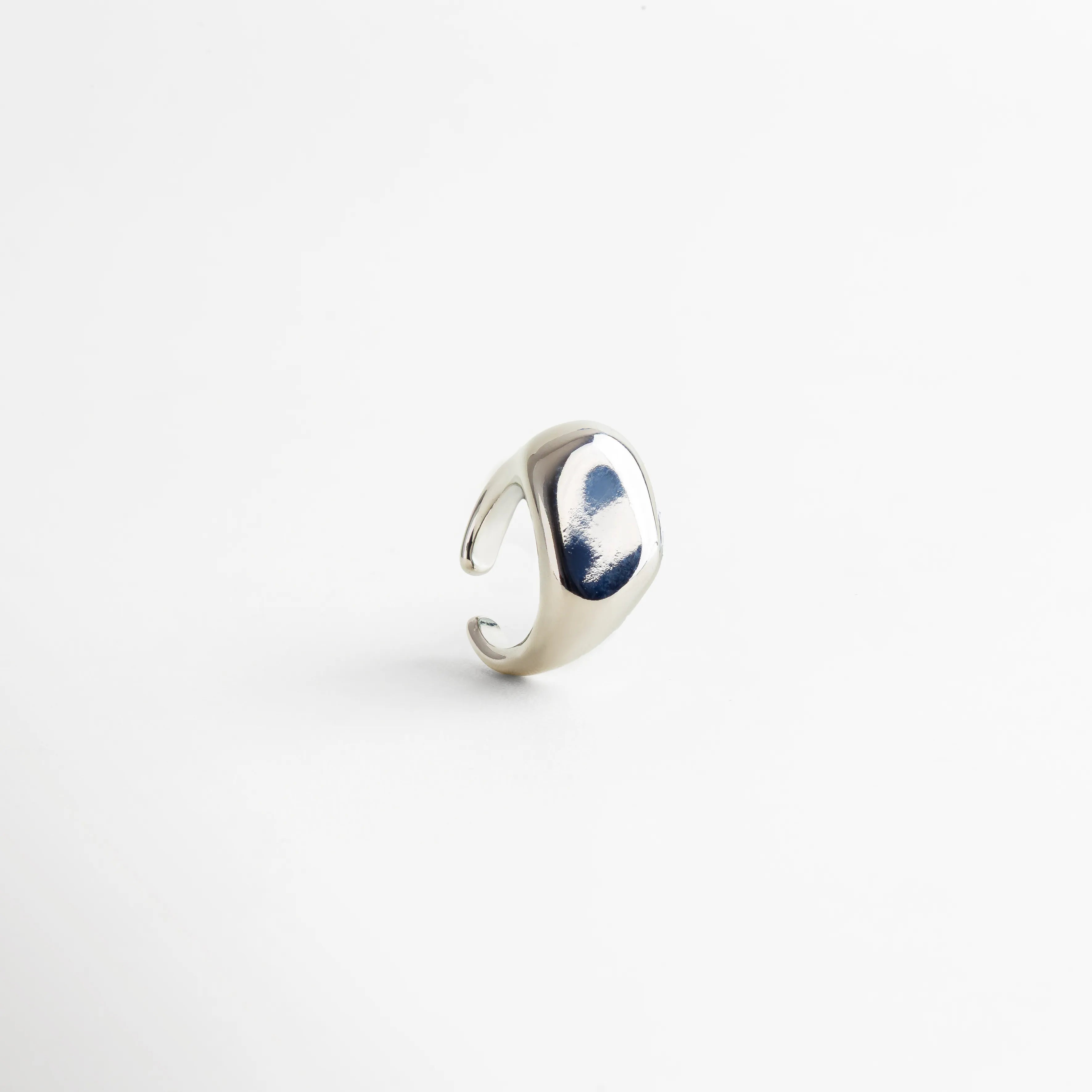 Anillo plateado ajustable con acabado pulido tipo espejo, diseño contemporáneo de superficie curva y bordes suaves que reflejan la luz con elegancia.