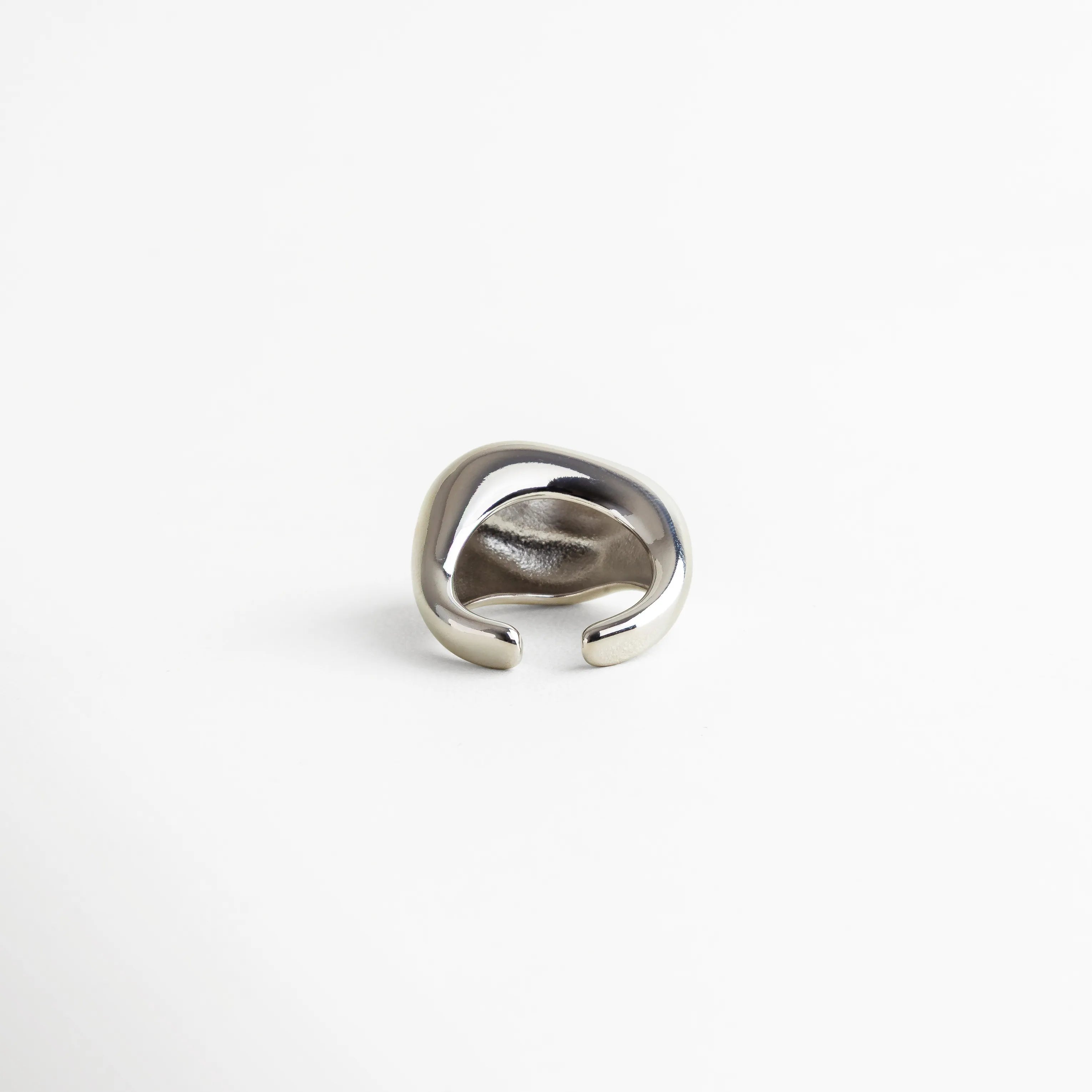 Anillo plateado con interior liso y diseño abierto, joya moderna con acabado brillante y forma ergonómica.