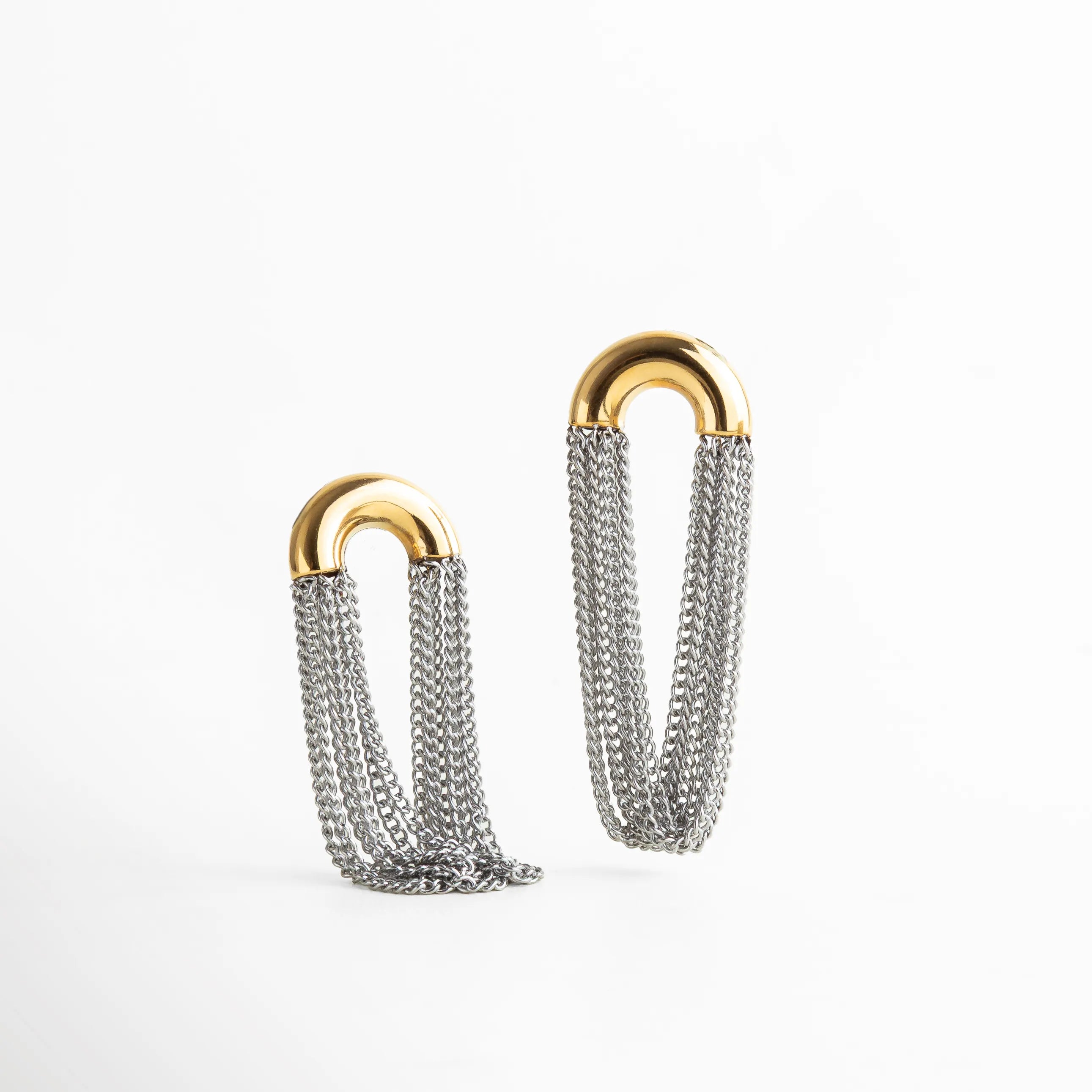 Aretes largos dorado con plateado, compuestos por múltiples cadenas metálicas que aportan movimiento y elegancia contemporánea.