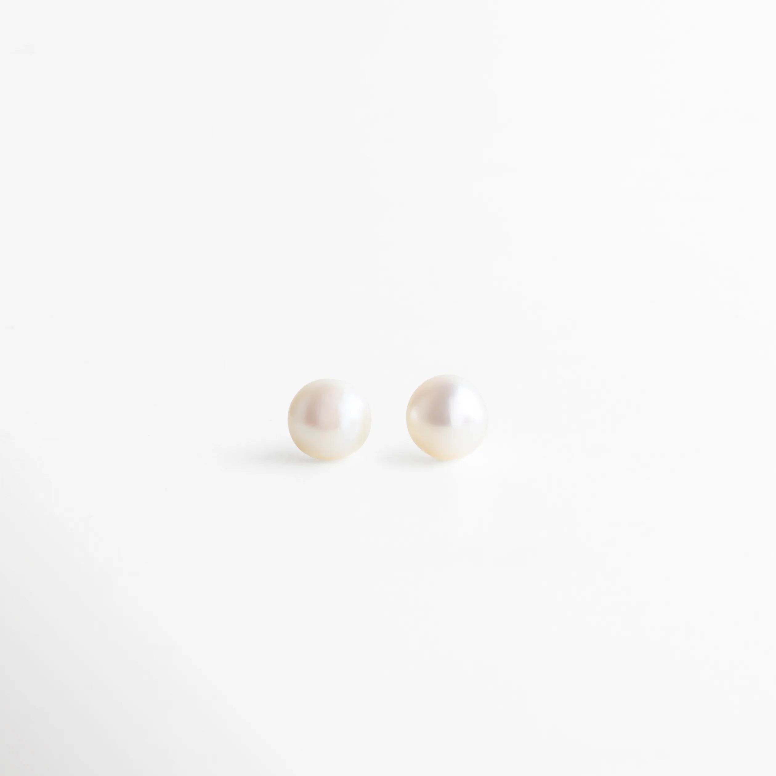 Aretes de perla blanca con base dorada, diseño delicado y versátil ideal para complementar cualquier look con elegancia.