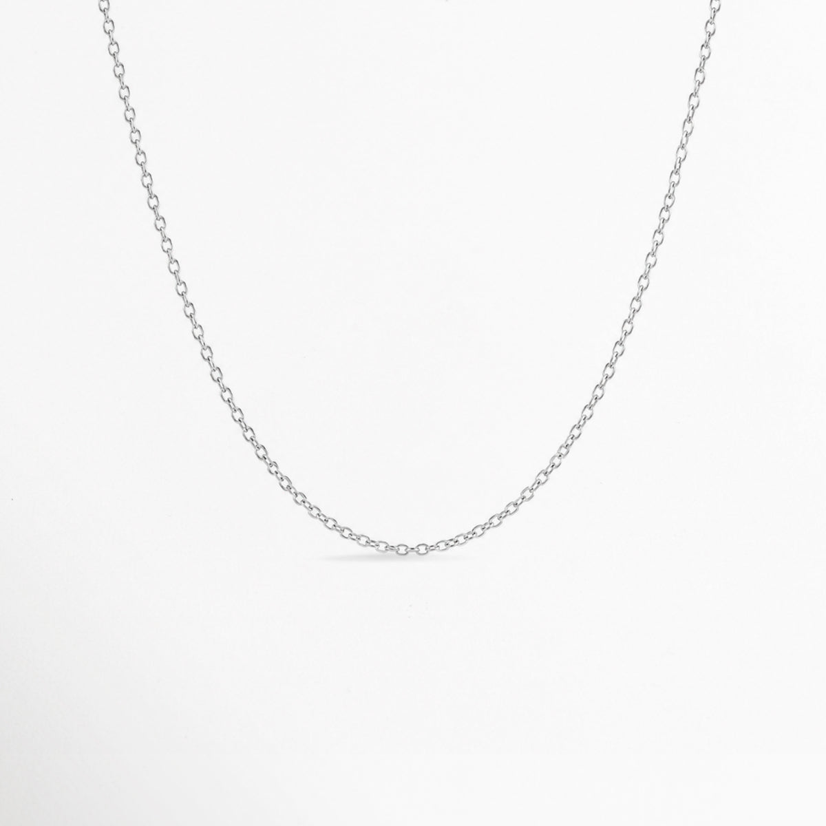 Cadena Simple Plateada de eslabones finos tipo forzatina/cable en tono plata con pulido brillante, vista frontal suspendida sobre fondo blanco, Cadena fina plateada de 45 cm de estilo minimalista enchapada en oro blanco o rodio, Vista de frente de collar de eslabones delgados y delicados en tono plata sobre superficie clara, Cadena básica plateada ajustable ideal para dijes y charms en toma de plano medio.