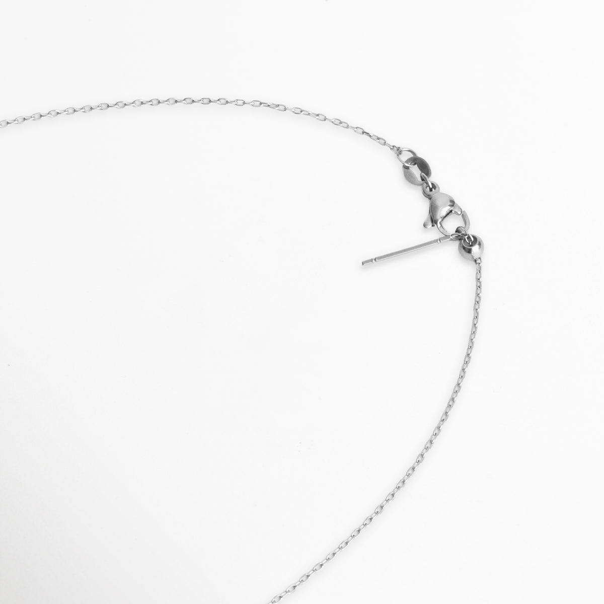Detalle del cierre de reasa de langosta o marinero con cadena de extensión ajustable y chapita de marca, Acercamiento al broche de seguridad y eslabones de ajuste de la Cadena Simple Plateada, Vista de cerca del mecanismo de cierre plateado enchapado sobre fondo blanco, Detalle del sistema de ajuste de longitud de la cadena delgada en tono plata.