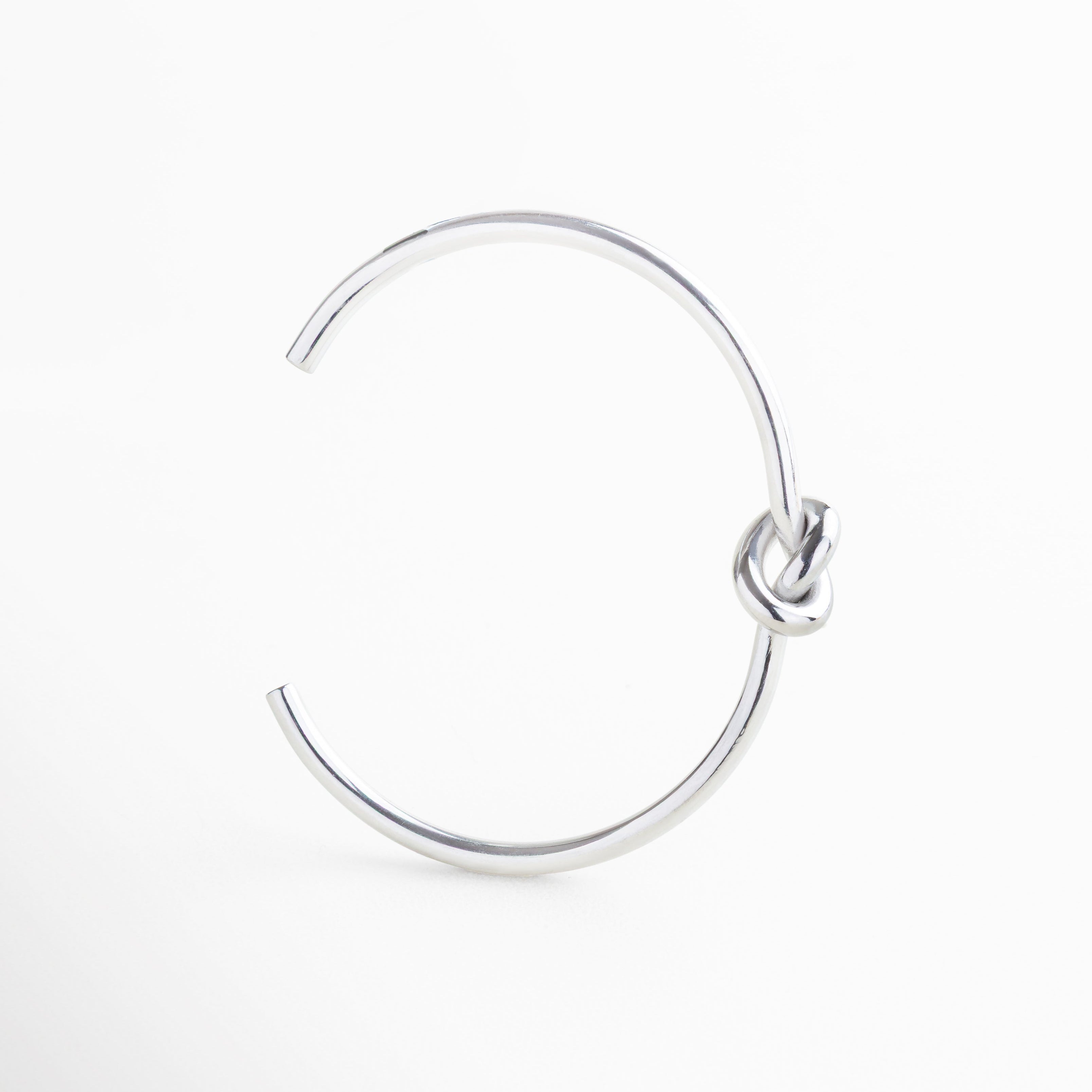 Pulsera rígida de 0.3 cm de ancho con diseño delgado, Proporción sutil del brazalete con nudo central, Joya plateada de diseño delgado y acabado pulido, Pulsera liviana con estructura firme y elegante