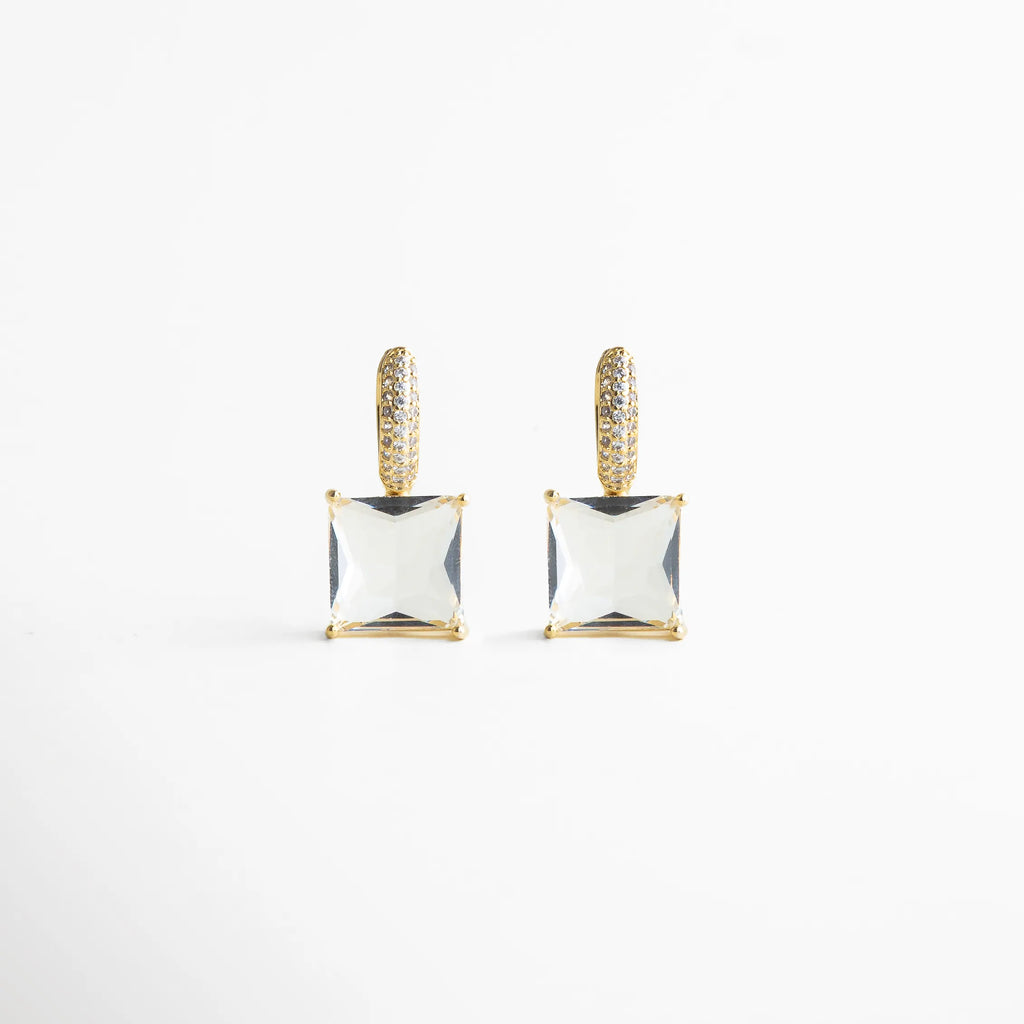 Vista frontal pareja de los aretes mostrando simetría perfecta: argolla pavé dorada y cristal cuadrado suspendido. Su estética pulida y minimalista aporta glamour sin esfuerzo, ideal para elevar un outfit de noche o un look más chic de día.