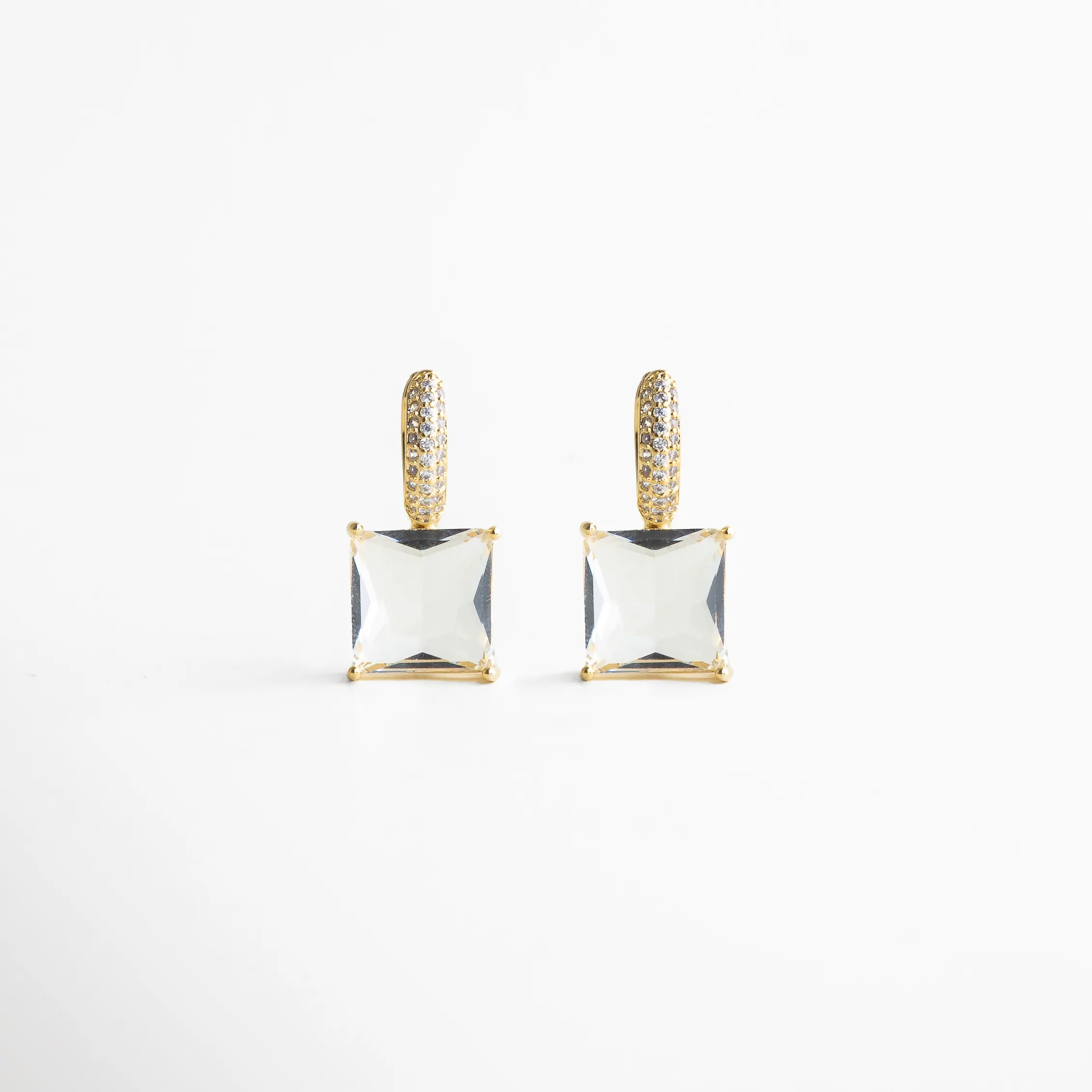 Vista frontal pareja de los aretes mostrando simetría perfecta: argolla pavé dorada y cristal cuadrado suspendido. Su estética pulida y minimalista aporta glamour sin esfuerzo, ideal para elevar un outfit de noche o un look más chic de día.