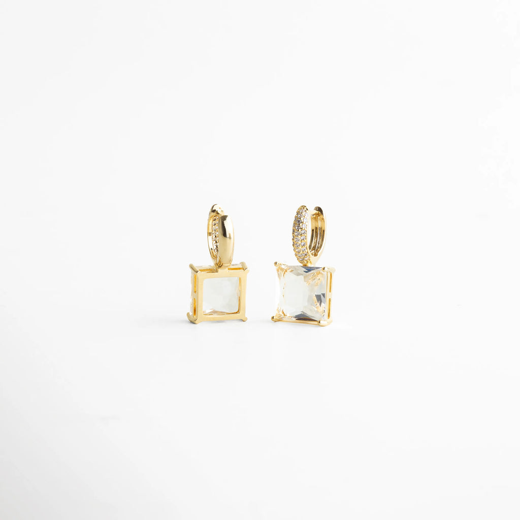 Vista lateral resaltando la estructura del engaste y el volumen del cristal cuadrado. El baño dorado contrasta con la transparencia del cristal creando un efecto luminoso elegante y nítido, perfecto para quienes buscan joyería moderna con acabado fino.