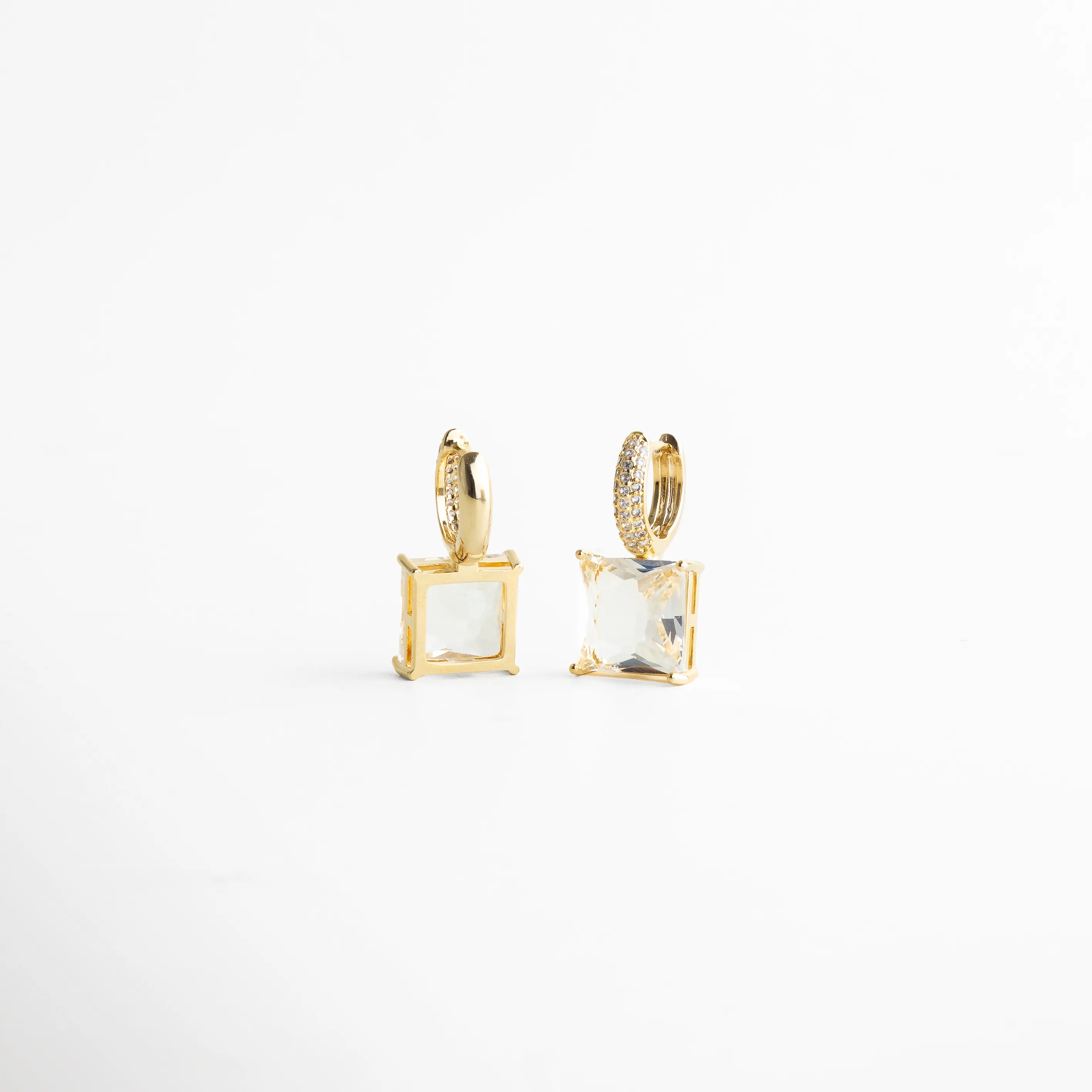 Vista lateral resaltando la estructura del engaste y el volumen del cristal cuadrado. El baño dorado contrasta con la transparencia del cristal creando un efecto luminoso elegante y nítido, perfecto para quienes buscan joyería moderna con acabado fino.