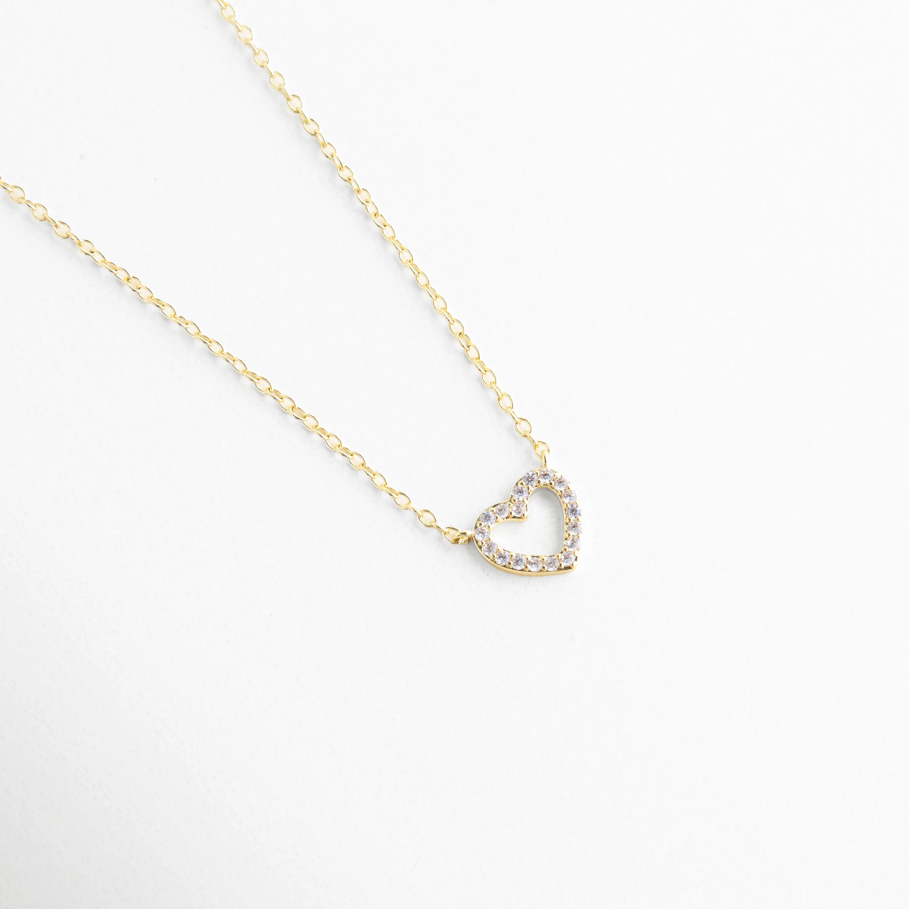 detalle de dije de corazón dorado, corazón dorado con acabado pulido, collar elegante con dije protagonista, joyería fina con diseño limpio, dije de corazón minimalista dorado, collar femenino de estética sofisticada