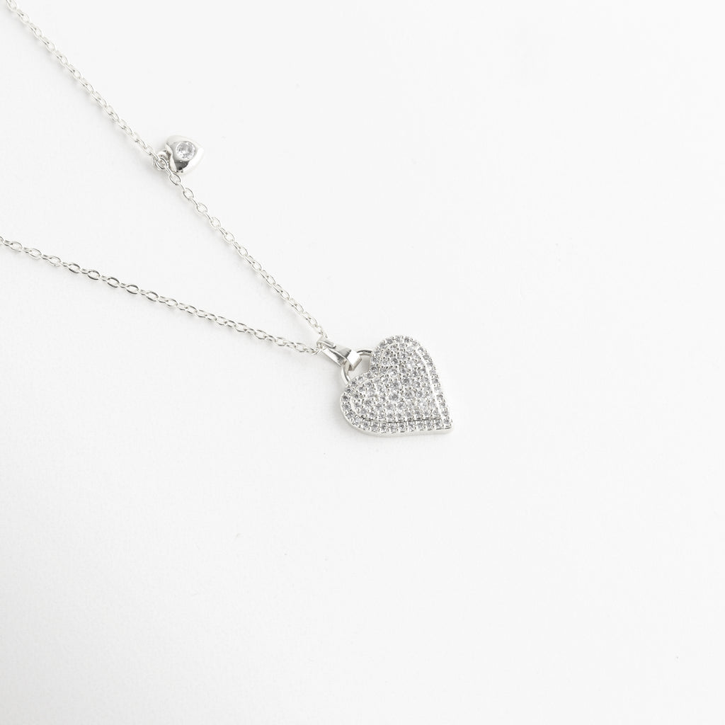Dije de corazón con pavé de piedras brillantes, Textura detallada del corazón con incrustaciones, Acabado brillante en dije de collar, Detalle cercano del corazón con diseño romántico, Micro piedras engastadas en forma de corazón