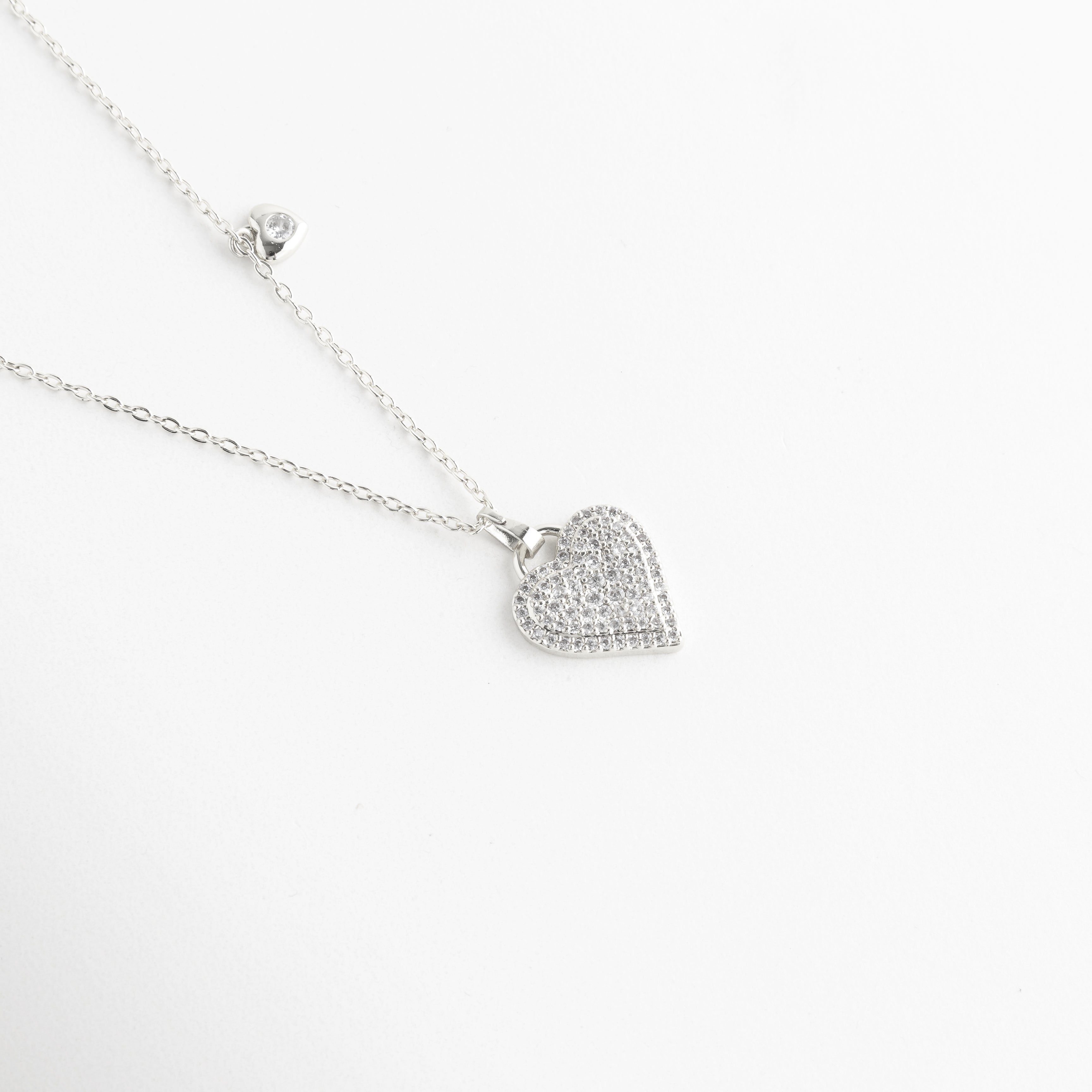 Dije de corazón con pavé de piedras brillantes, Textura detallada del corazón con incrustaciones, Acabado brillante en dije de collar, Detalle cercano del corazón con diseño romántico, Micro piedras engastadas en forma de corazón