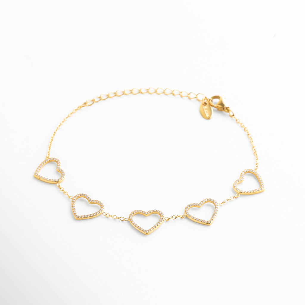 detalle de corazones en pulsera dorada, corazones dorados con acabado pulido, pulsera elegante con diseño romántico, joyería femenina con corazones delicados, pulsera dorada de estética sofisticada, detalle fino de pulsera de corazones