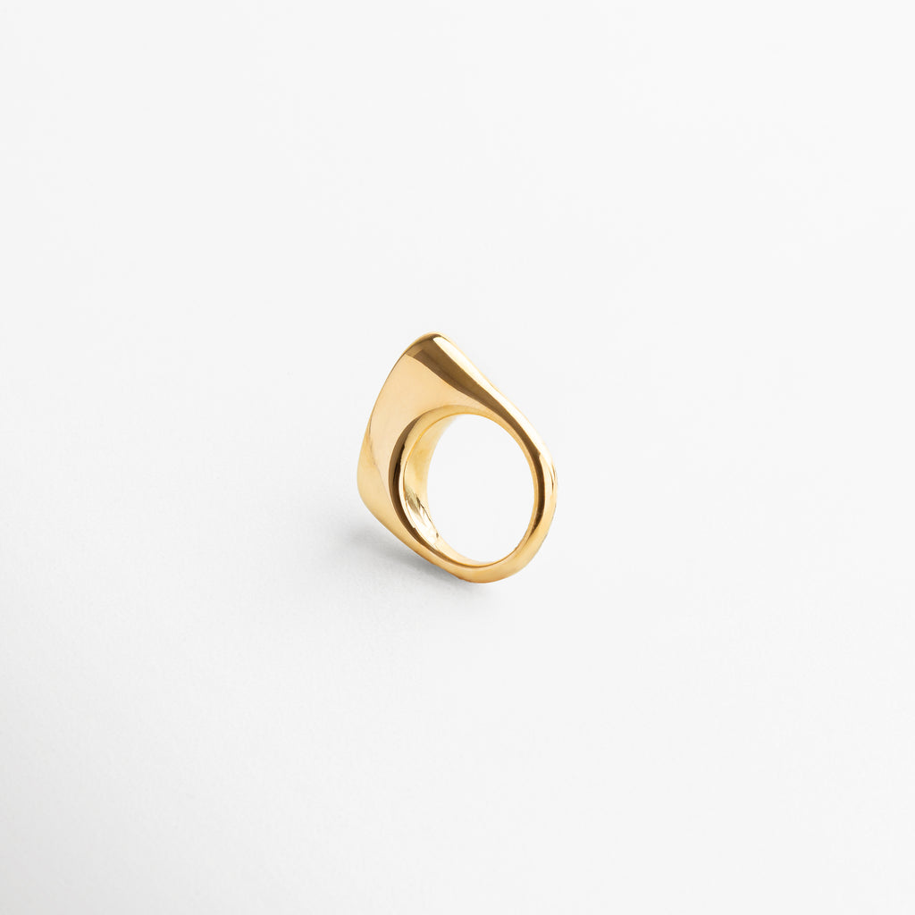 Anillo Génova Dorado visto desde el frente, mostrando su diseño asimétrico y acabado brillante en chapa de oro de 18K. Vista frontal del anillo Génova, con forma única y moderna en tono dorado sobre acero inoxidable. Anillo statement en dorado, con silueta artística y diseño contemporáneo capturado desde el frente.Frontal del anillo Génova Dorado, destacando su estilo audaz y sofisticado.
Primer plano del anillo Génova en dorado, vista frontal que resalta su originalidad y volumen.