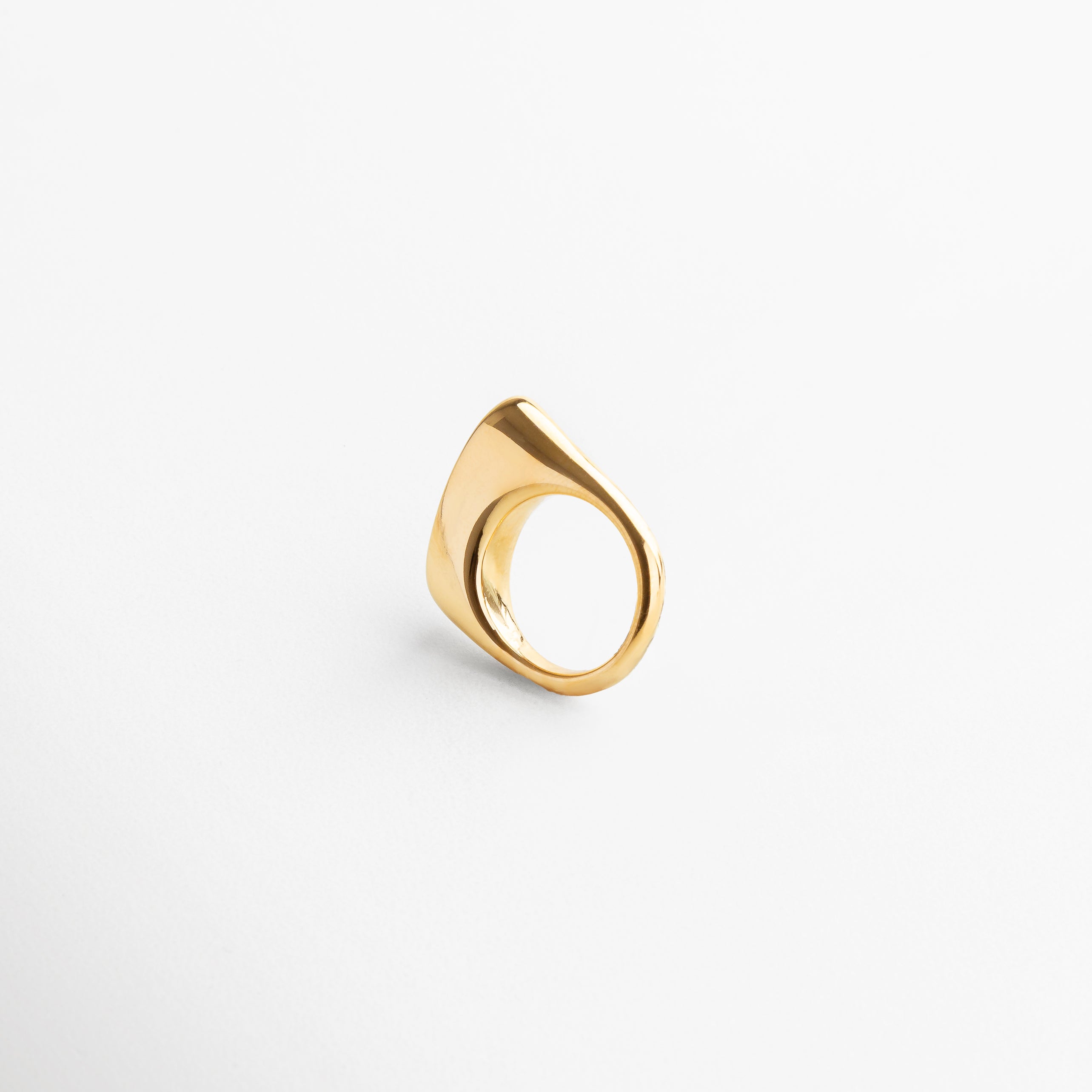 Anillo Génova Dorado visto desde el frente, mostrando su diseño asimétrico y acabado brillante en chapa de oro de 18K. Vista frontal del anillo Génova, con forma única y moderna en tono dorado sobre acero inoxidable. Anillo statement en dorado, con silueta artística y diseño contemporáneo capturado desde el frente.Frontal del anillo Génova Dorado, destacando su estilo audaz y sofisticado.
Primer plano del anillo Génova en dorado, vista frontal que resalta su originalidad y volumen.