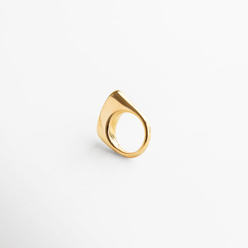 Anillo Génova Dorado visto desde el frente, mostrando su diseño asimétrico y acabado brillante en chapa de oro de 18K. Vista frontal del anillo Génova, con forma única y moderna en tono dorado sobre acero inoxidable. Anillo statement en dorado, con silueta artística y diseño contemporáneo capturado desde el frente.Frontal del anillo Génova Dorado, destacando su estilo audaz y sofisticado.
Primer plano del anillo Génova en dorado, vista frontal que resalta su originalidad y volumen.