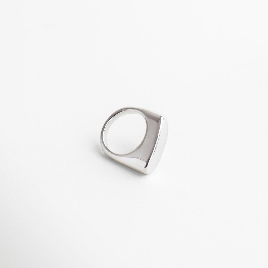 Vista superior del anillo Génova Plateado, mostrando su estructura asimétrica y acabado pulido.Anillo moderno Génova visto desde arriba, con diseño abstracto en acero inoxidable brillante. Toma cenital del anillo Génova Plateado, con forma única y estilo minimalista con carácter. Perspectiva superior del anillo en tono plateado, ideal para destacar en combinaciones creativas. Vista desde arriba del anillo Génova, con acabado metálico frío y diseño escultural