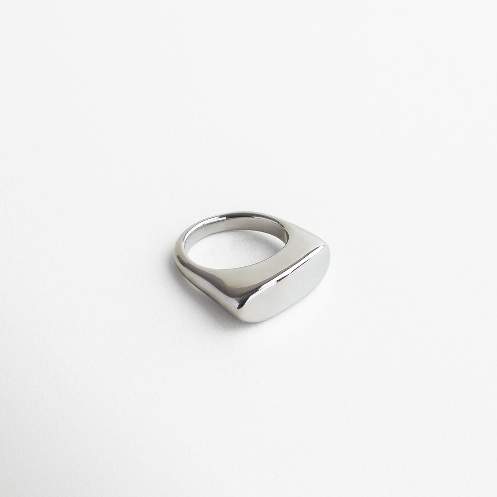 Anillo Génova Plateado visto desde el frente, con diseño asimétrico y acabado metálico brillante. Frontal del anillo Génova en acero inoxidable plateado, resaltando su estilo moderno y artístico. Vista frontal del anillo Génova Plateado, con silueta única y sofisticada. Primer plano del anillo Génova en tono plateado, destacando su diseño disruptivo y elegante. Anillo plateado de acero inoxidable desde el frente, con forma audaz y contemporánea.