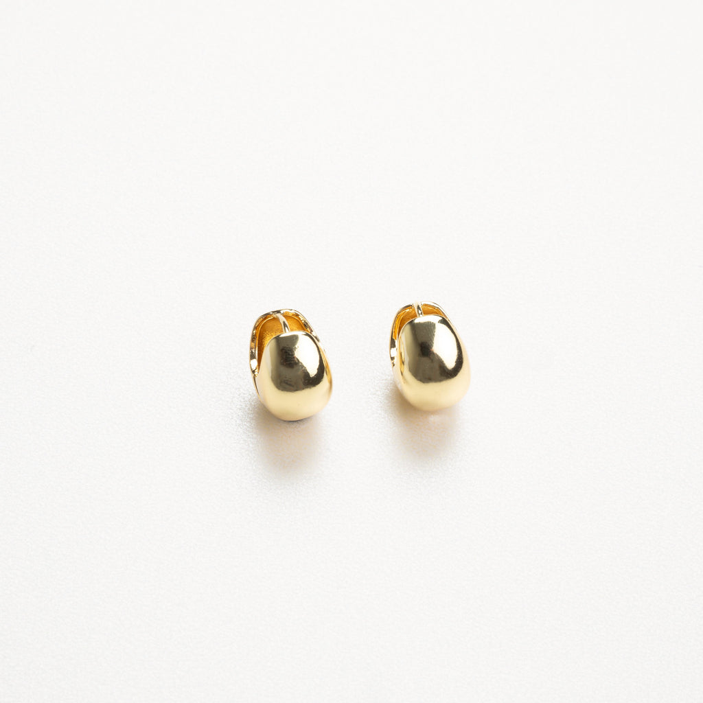 aretes dorados de estilo minimalista vistos de perfil, con acabado brillante
