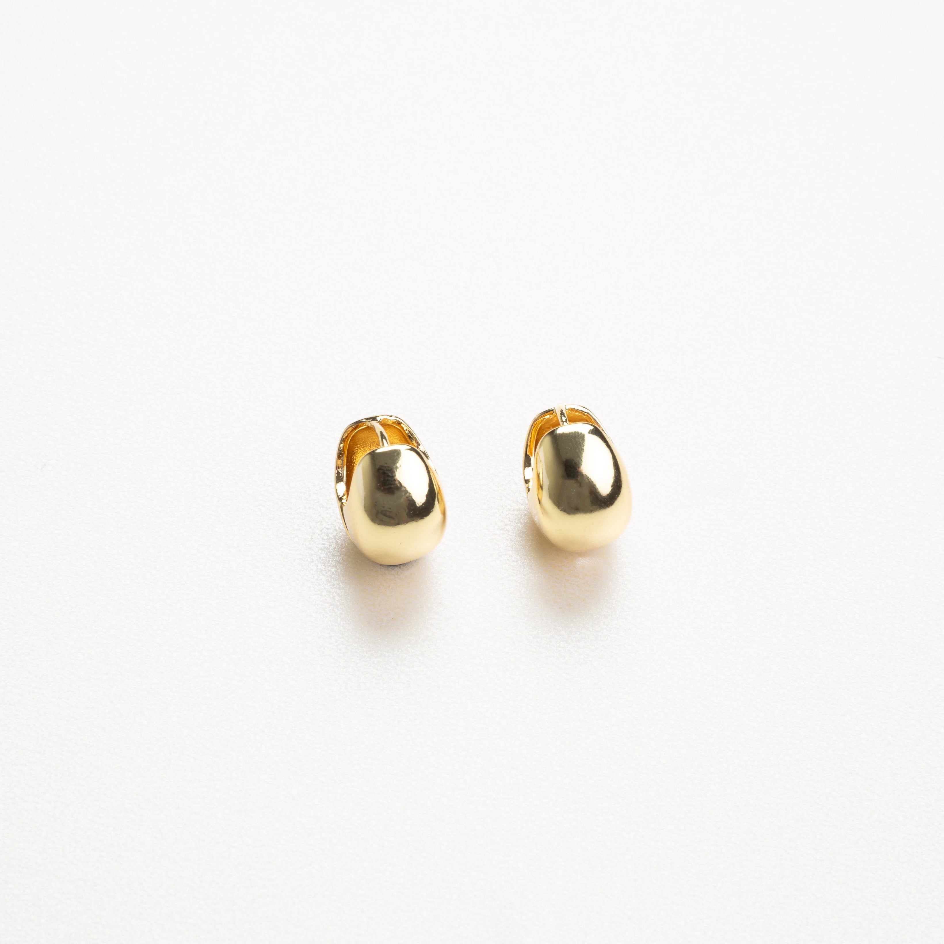 aretes dorados de estilo minimalista vistos de perfil, con acabado brillante