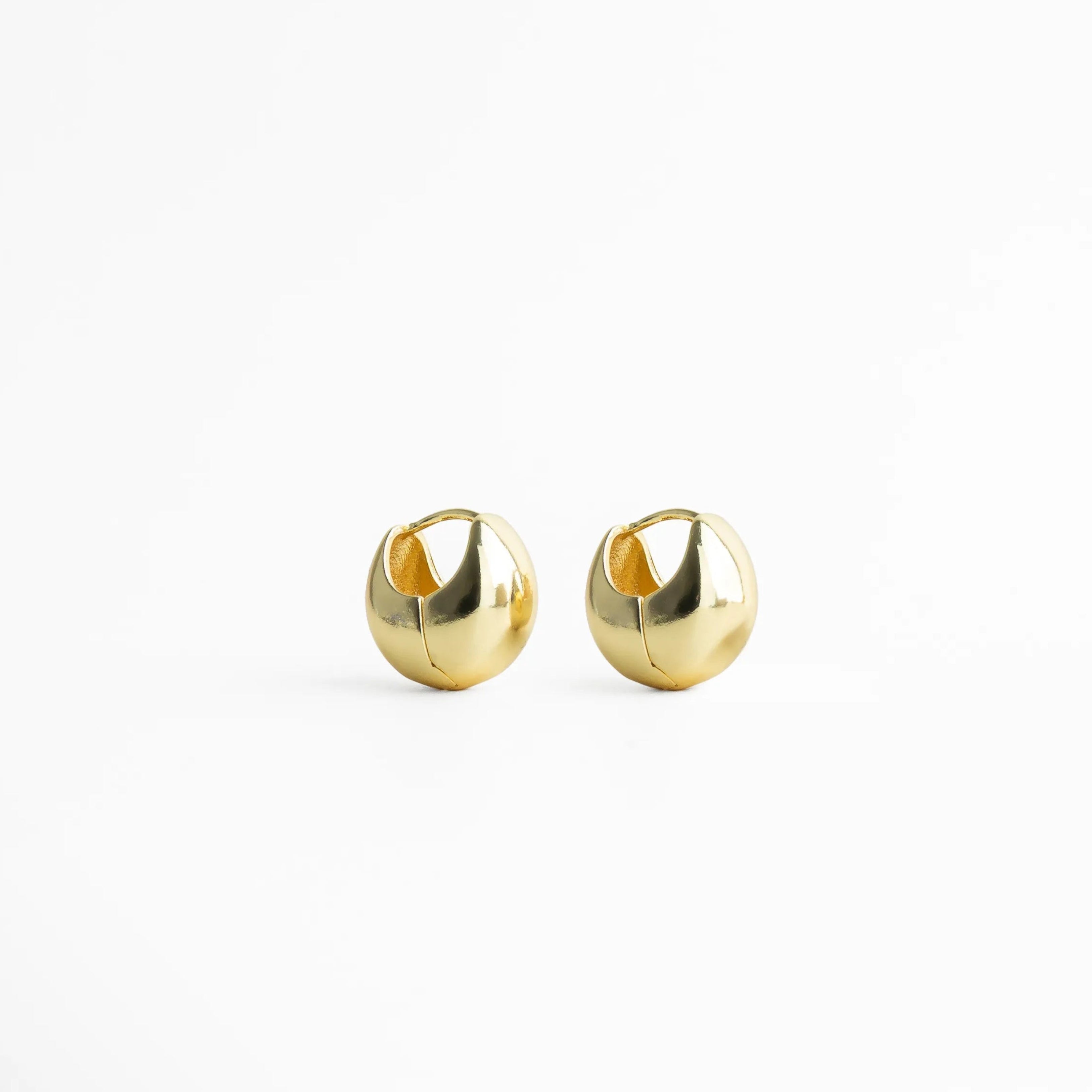 Aretes dorados tipo stud con diseño redondeado y acabado pulido espejo, joyería minimalista elegante ideal para uso diario.