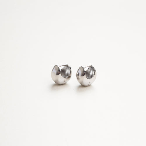 Aretes sencillos en acabado plateado vistos de lado, estilo discreto y moderno