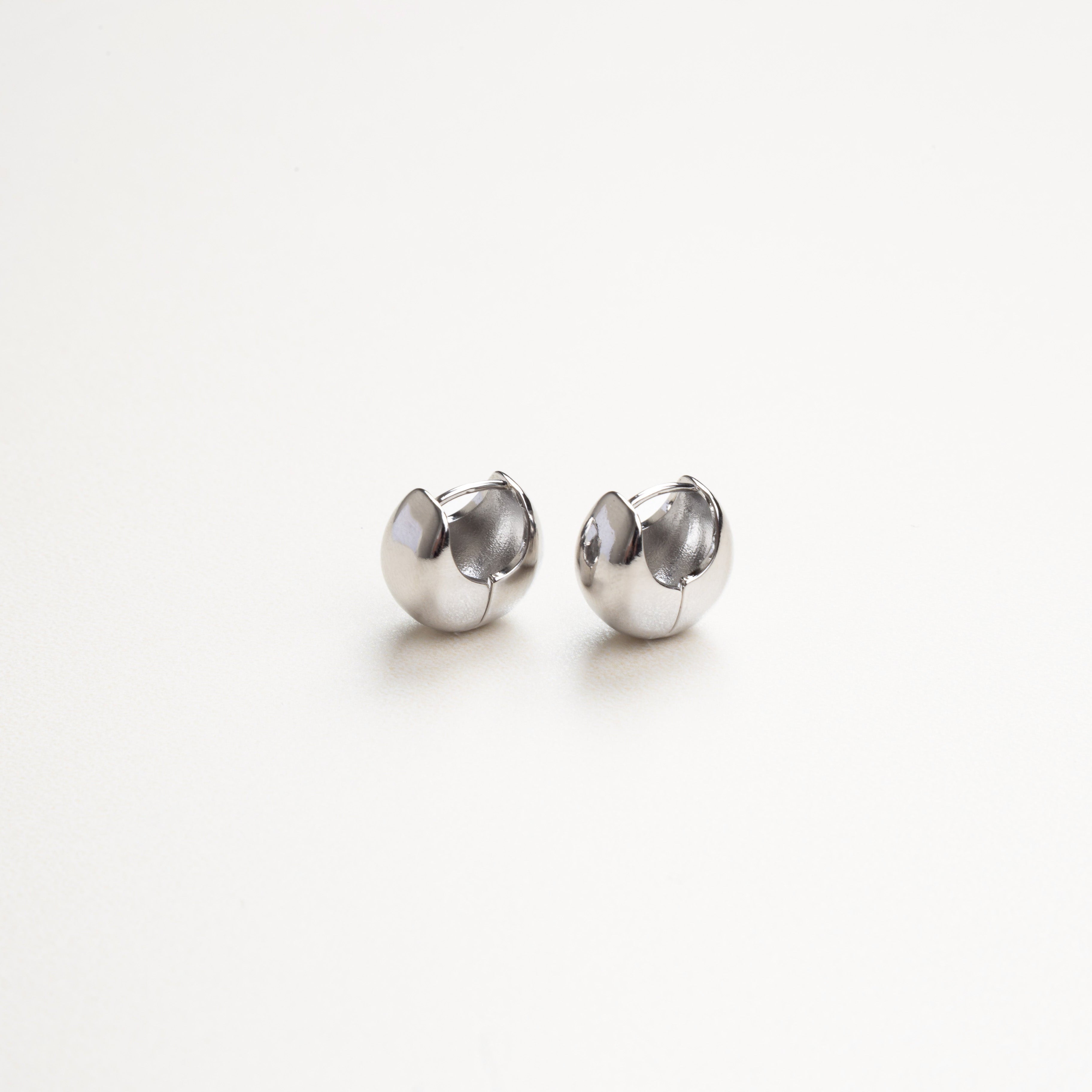 Vista frontal de aretes plateados sencillos, diseño limpio y minimalista
