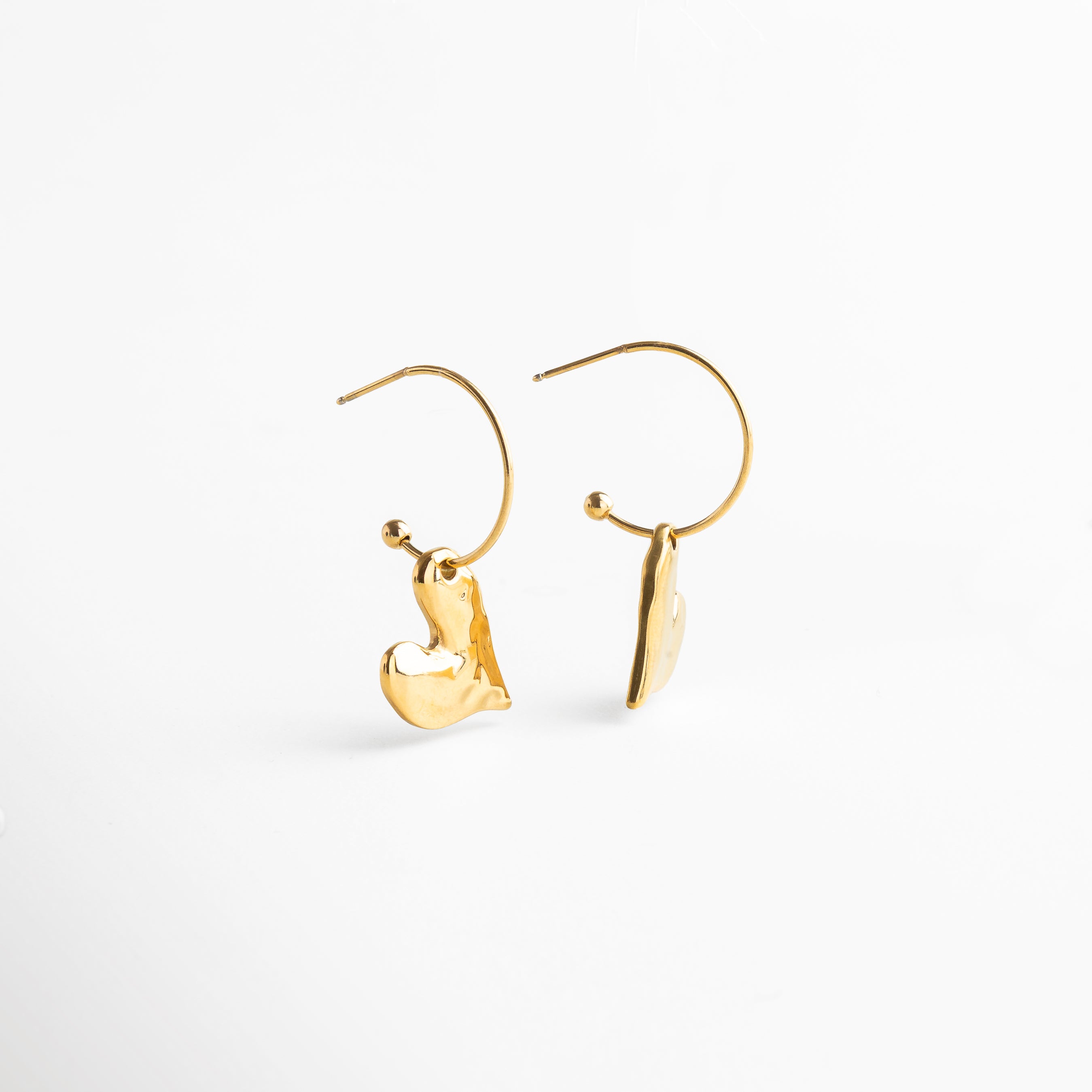 Aretes corazón dorado vistos en ángulo elegante, Perfil del pendiente Amour con diseño curvo, Movimiento sutil de aretes dorados con forma orgánica, Vista angular de corazón moderno en acabado brillante