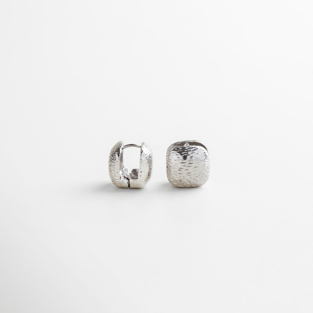 Vista superior del Anillo Idriss plateado, con diseño de 2.5 cm lleno de brillo gracias a sus zirconias incrustadas. Toma cenital del anillo en acabado plateado, con detalles que evocan elegancia clásica y moderna. Anillo de plata 925 con zirconias visto desde arriba, mostrando su forma estilizada y brillante. Perspectiva superior del Anillo Idriss plateado, con distribución armoniosa de las piedras brillantes. Vista desde arriba del anillo plateado, con forma alargada y acabado reluciente.