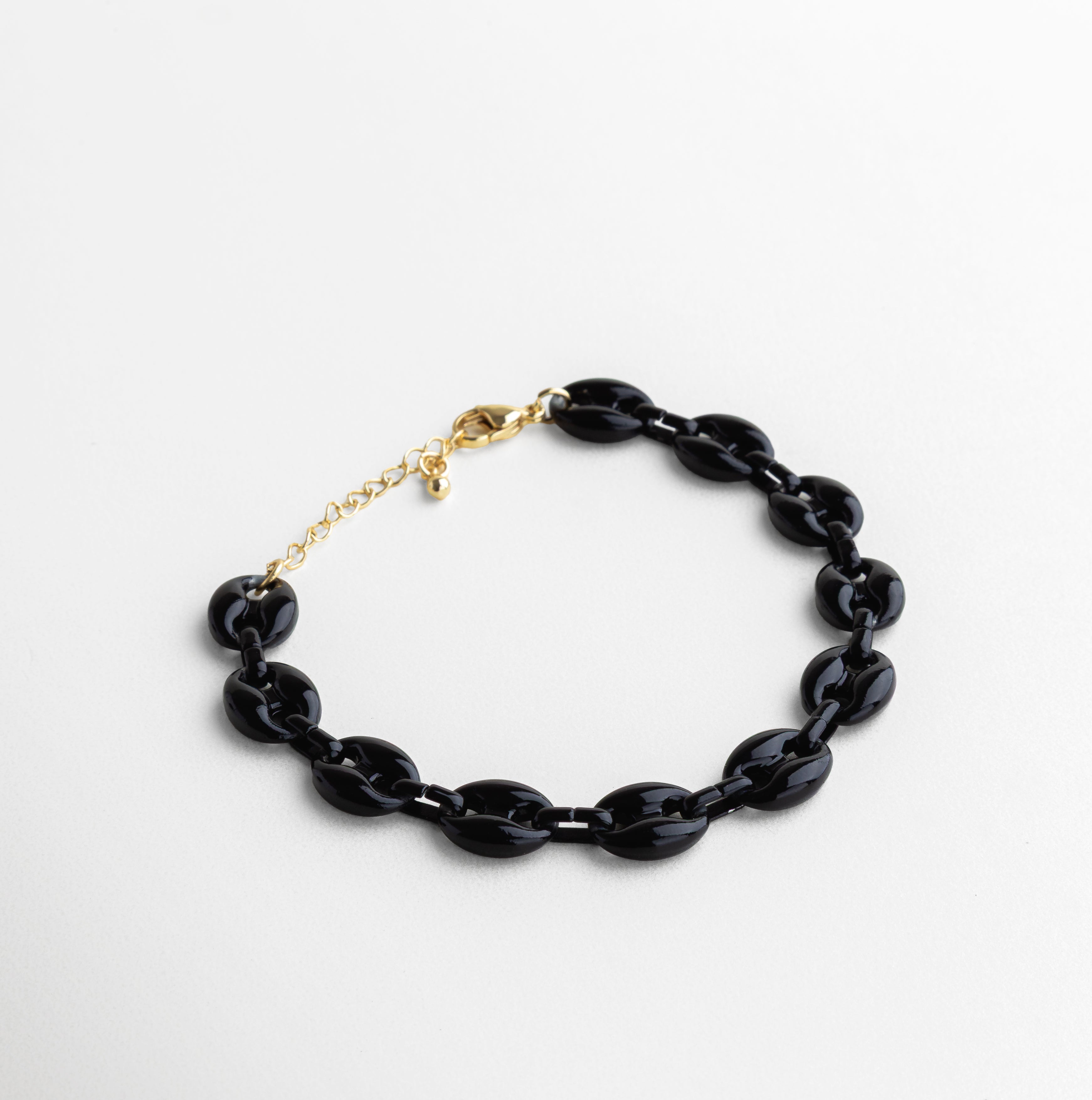 Pulsera negra con eslabones acrílicos y chapa de oro 18K, Pulsera elegante con contraste entre negro intenso y dorado, Diseño moderno en negro brillante con acabado dorado, Accesorio minimalista en negro con detalles metálicos