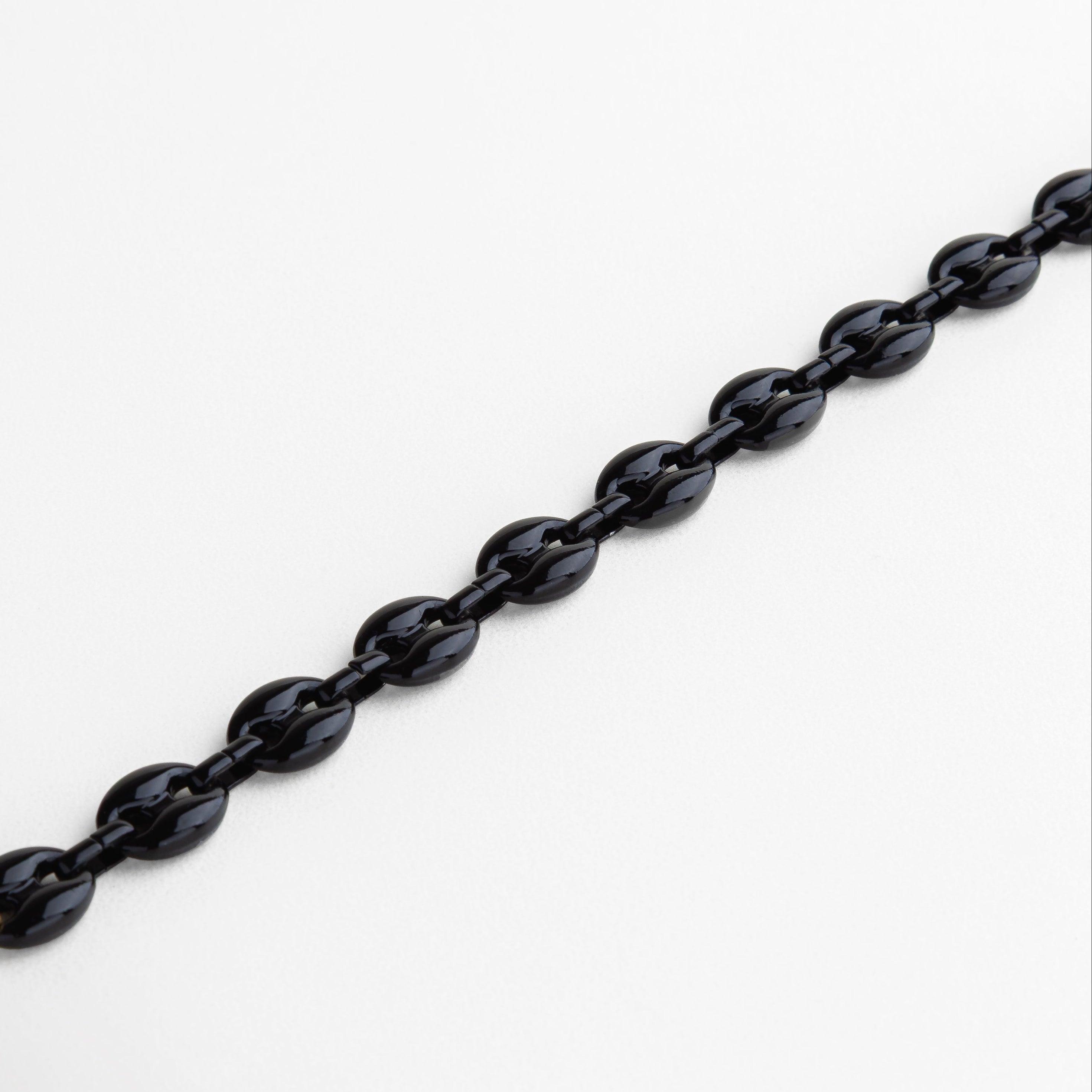 Pulsera de eslabones ovalados negros colocada en línea recta mostrando el diseño de cadena.