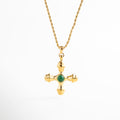 Collar dorado con dije de cruz desestructurada y piedra verde, Collar con cruz irregular y centro de piedra verde sintética, Joya dorada con cruz moderna y detalle vibrante, Collar chapado en oro con dije en forma de cruz contemporánea
