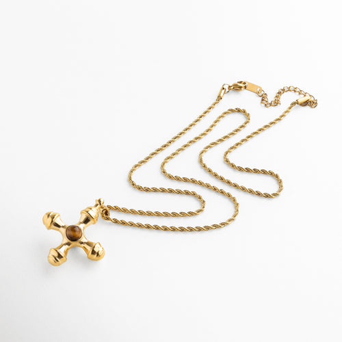 Detalle del dije en cruz dorada con piedra Ojo de Tigre, Primer plano del Ojo de Tigre en cruz dorada, Textura de la piedra Ojo de Tigre en cruz asimétrica, Brillo del acabado dorado y vetas cálidas del Ojo de Tigre